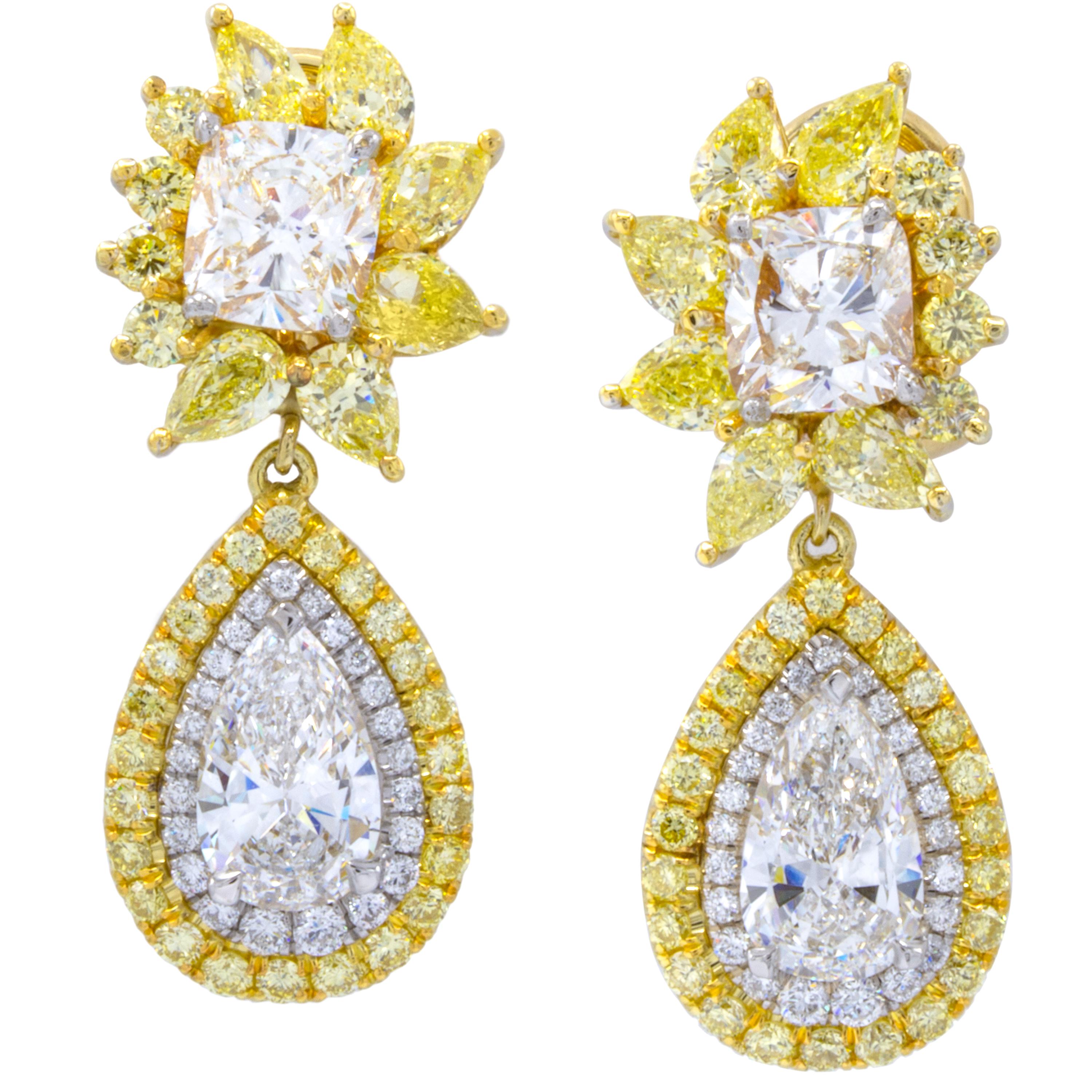 A delectable pair of flowery diamond dangle earrings display incredible color within 2.98 carats of natural fancy intense yellow pear shape diamonds. Nestled between lay perfectly matched white cushion cut diamonds and pear shaped drops surrounded