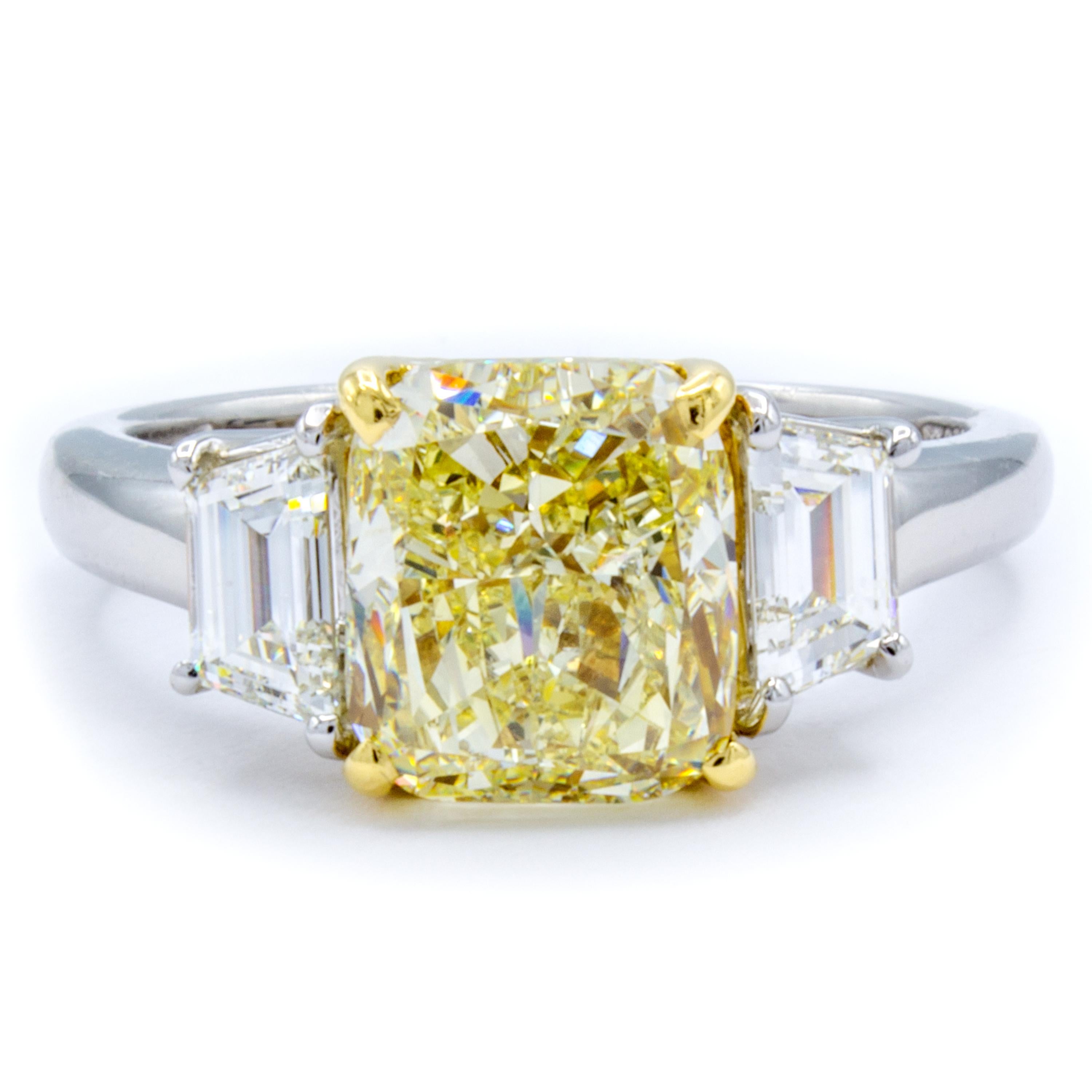 A GIA certified 3.01 carat cushion cut diamond bridles with a rare natural fancy light yellow color within a band of platinum and 18Kt yellow gold. At each side, step-cut trapezoid side diamonds reflect a fiery support. Designed by David