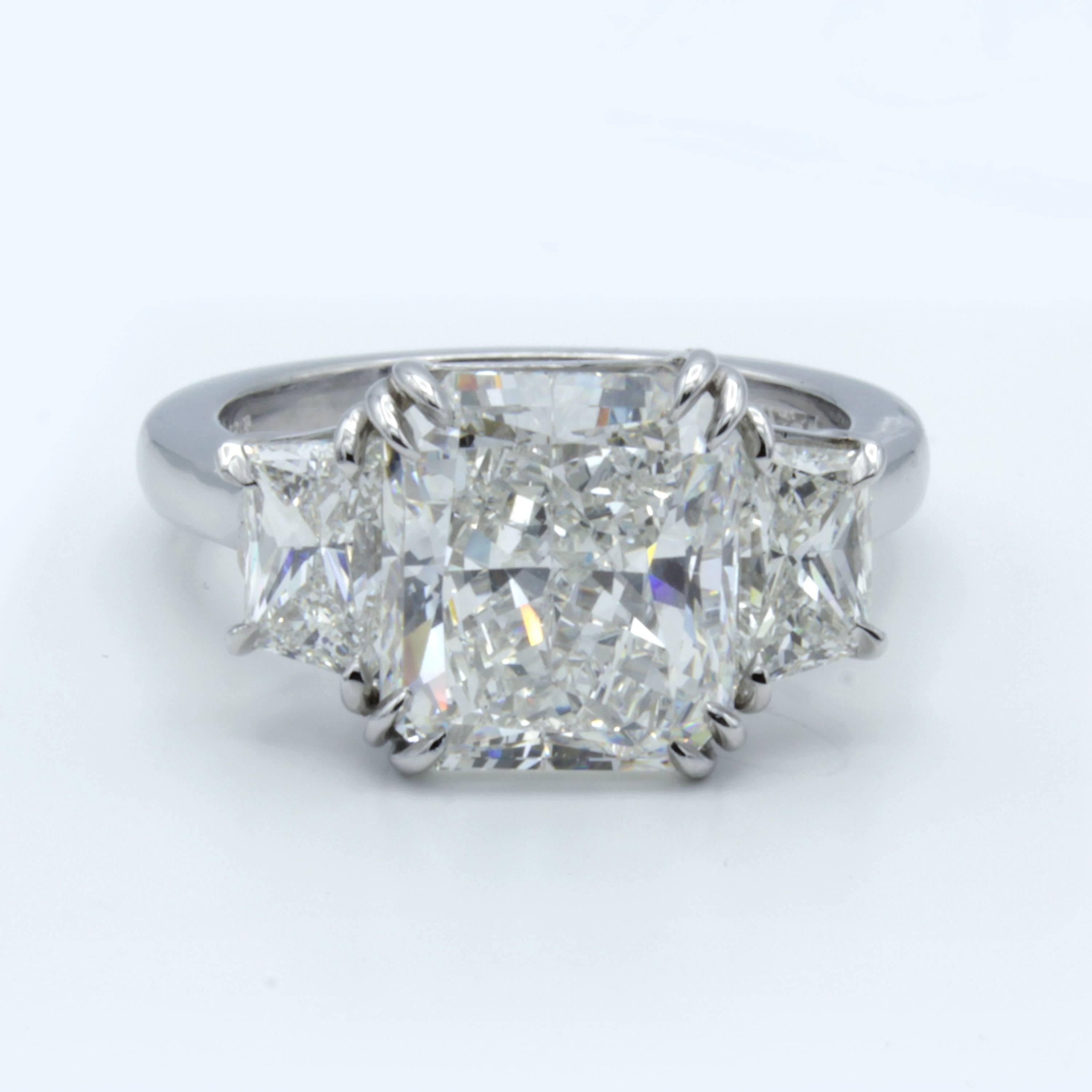 This Rosenberg Diamonds & Co. engagement ring shows an incredible 4.34 carat radiant cut diamond within a band of bright platinum. At each side shine beautiful trapezoid diamond side stones highlighting the beautiful center stone perfectly.
 
