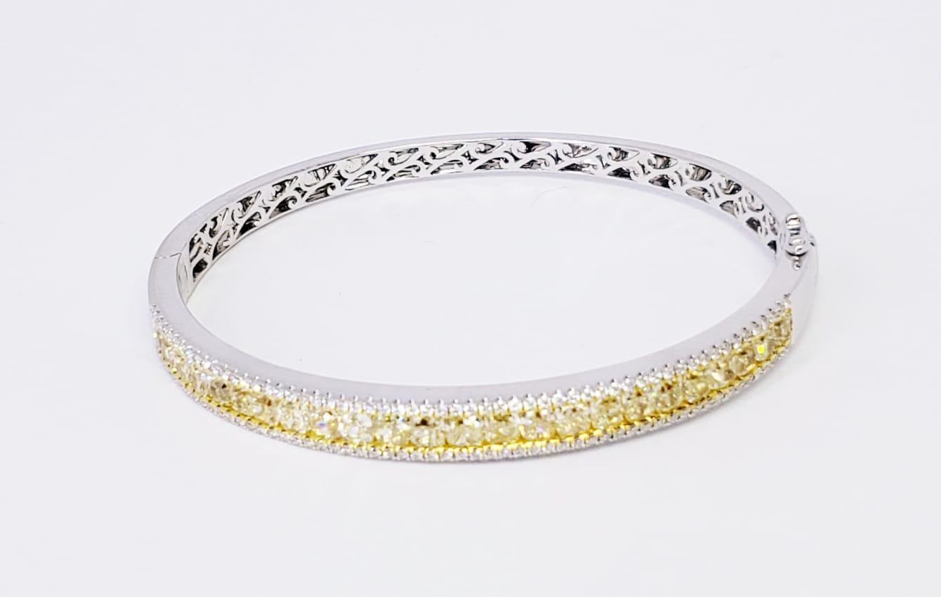 Rosenberg Diamonds & Co. 6.13 carat total weight Fancy Yellow Diamond bangle. This beautiful 18 karat white & yellow diamond bangle has twenty-four carefully matched fancy yellow cushion cut diamonds, surrounded by a single row of micro pave round