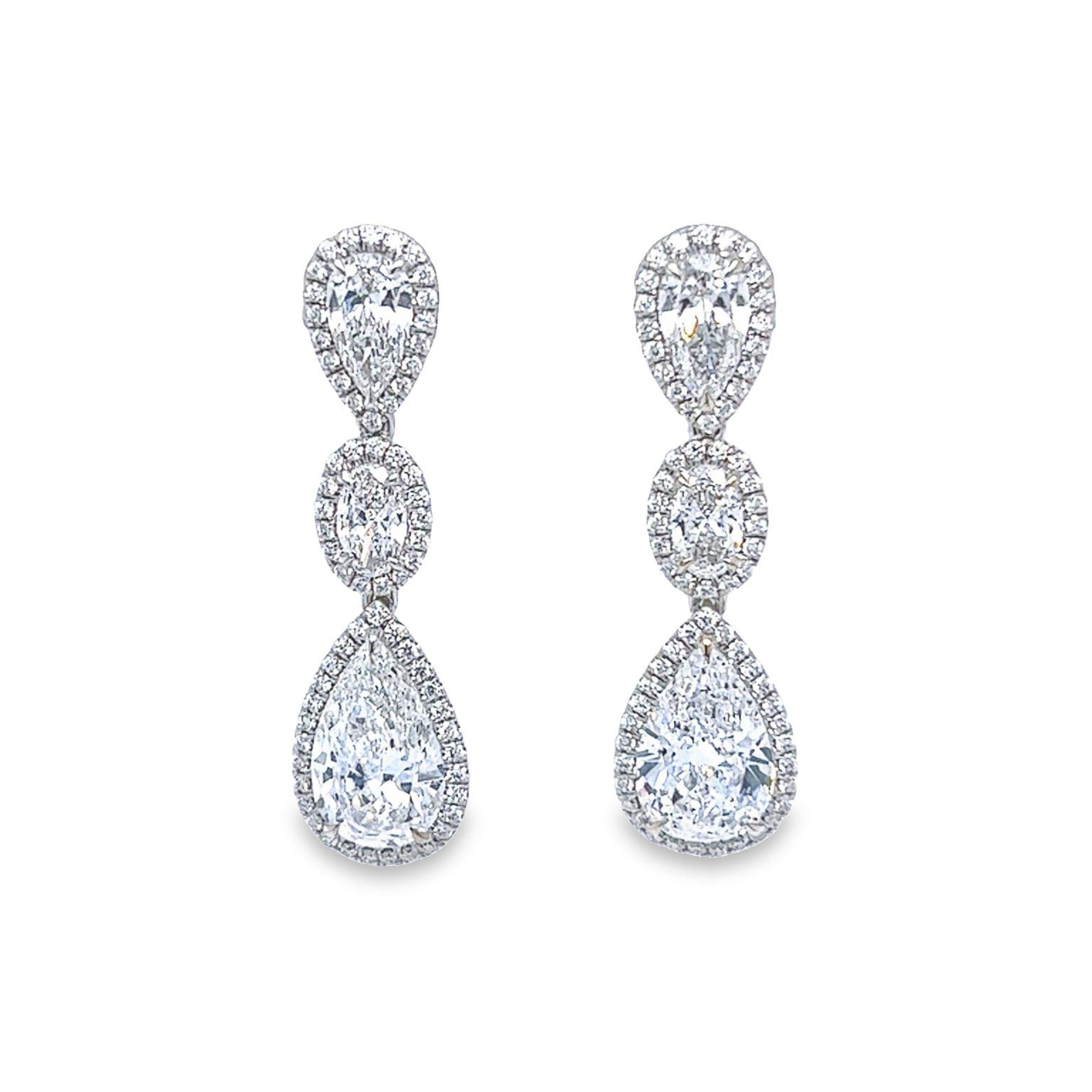 Get ready for a night out with this jaw dropping white diamond Pear & Oval shape earrings F in color SI2 clarity. This gorgeous 3 tier light weight earrings are set in 18k white gold and surrounded by a beautiful white halo with designed by David