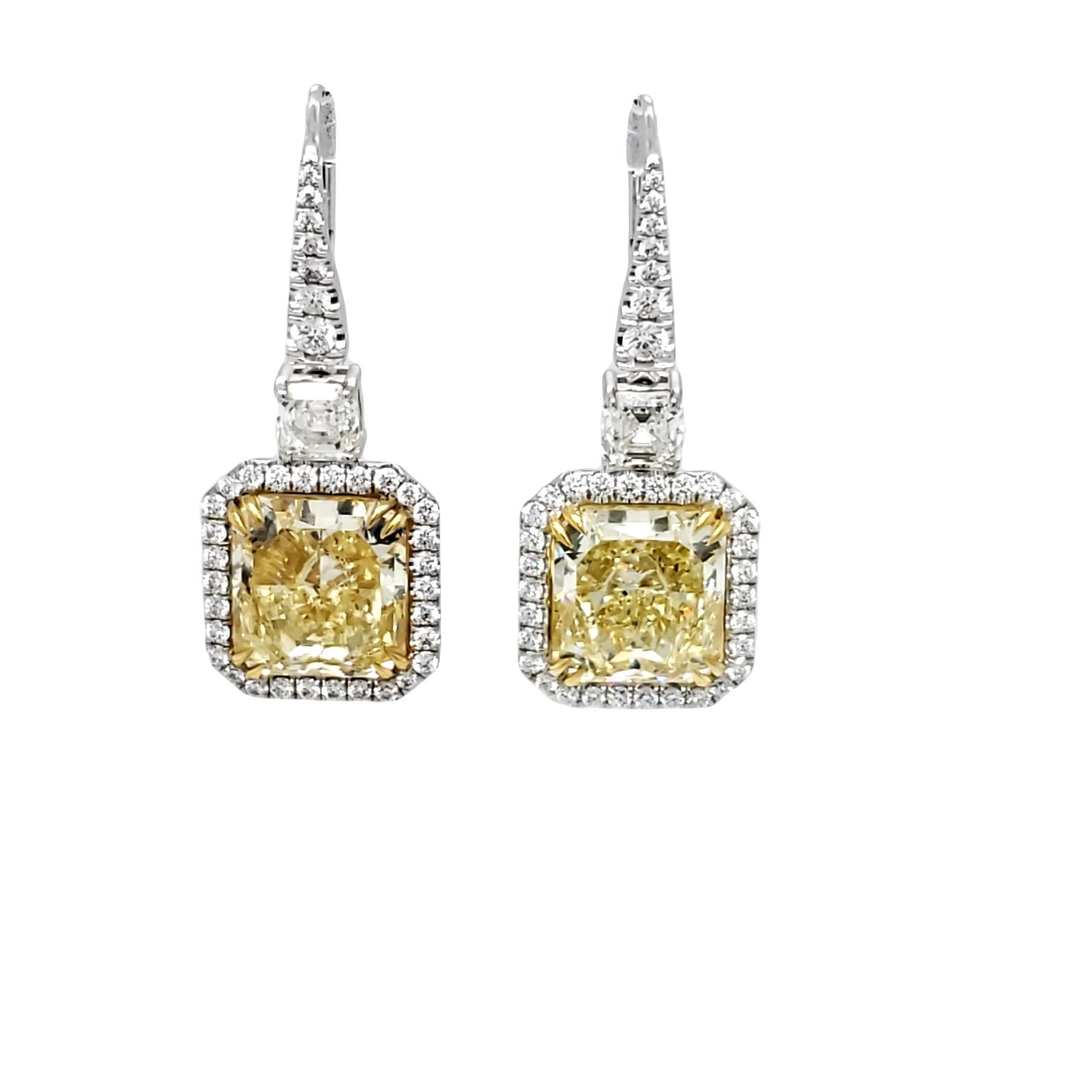A beautifully matched 9.68tw Radiant Fancy Yellow VVS2 clarity diamond earrings are GIA Certified. These gorgeous light weight dangling earrings set in 18k white and yellow gold also features a matched pair of 1.03 carat total weight of Asscher