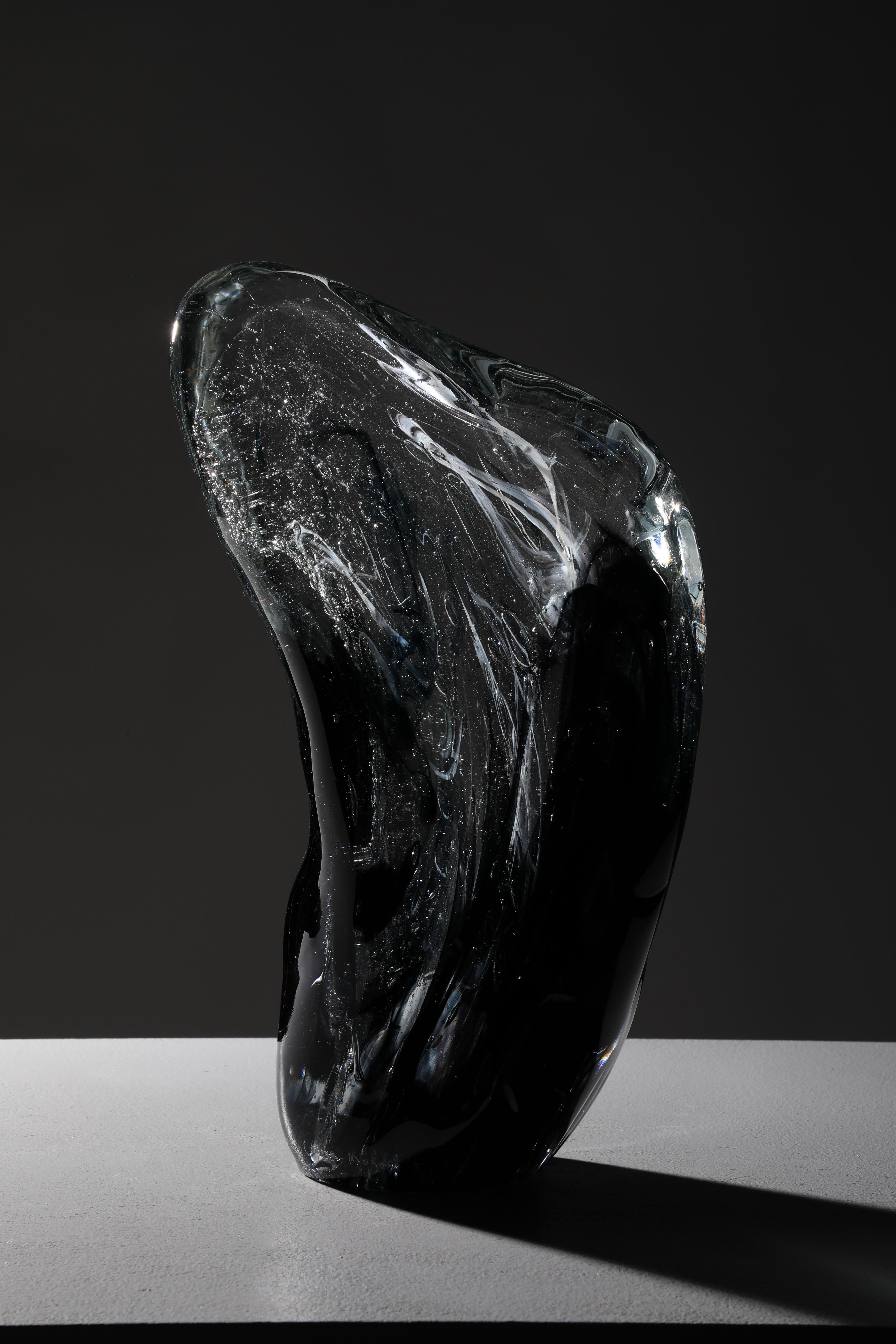 'Alcor' is a contemporary abstract cast glass sculpture by David Ruth from his Internal Space series. It is made by heating the glass and then hand working it into form. The main colors of black and dark blue contrasts the clear and white glass