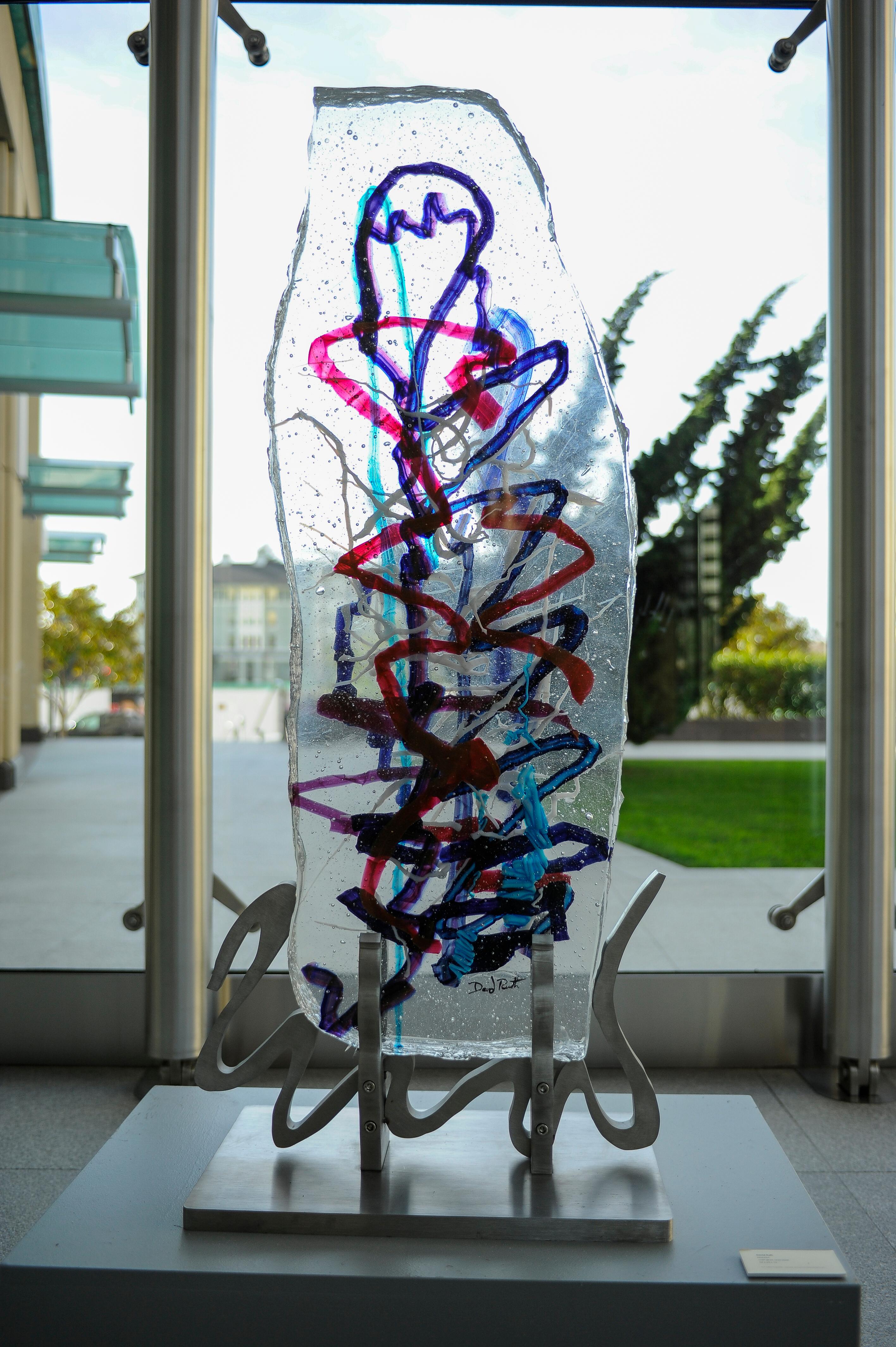 'Mandul' is a contemporary abstract cast glass sculpture by David Ruth from his Internal Space & Standing Stones series. It features painterly brushstroke formations in glass called trails. These trails of blue, black, red, white, and purple are