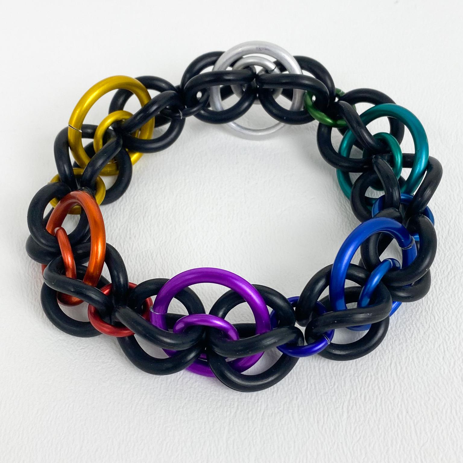 Questo spettacolare e raro bracciale modernista a maglie di David Spada New York presenta un iconico design anni '80 di A Space. Il bracciale a maglie vanta maglie in gomma nera completate da anelli distanziatori in alluminio anodizzato multicolore.