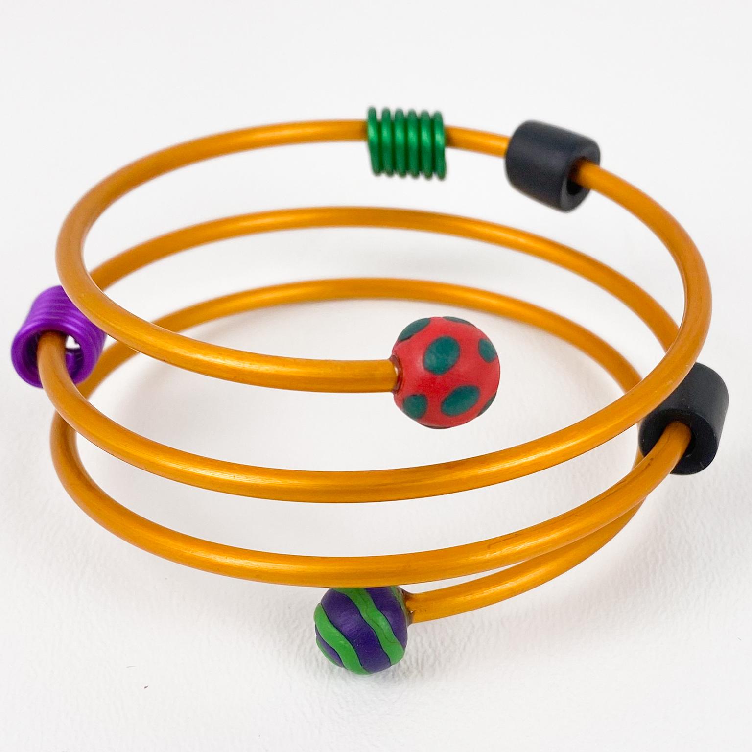 Esta rara pulsera brazalete modernista de David Spada de Nueva York presenta un genial diseño de la Era Espacial de los años 80. El brazalete presenta un diseño en espiral con aluminio anodizado naranja neón, adornado con elementos de goma negra,