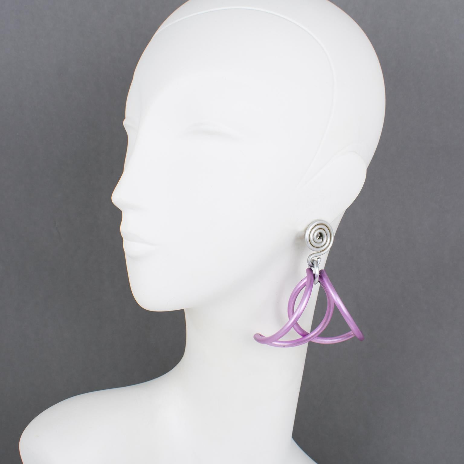 With a dangling dimensional and geometric coiled shape, these gorgeous modernist David Spada New York oversized pierced earrings have a fascinating Space Age 1980s design. They are made of anodized aluminum metal in silver and periwinkle purple