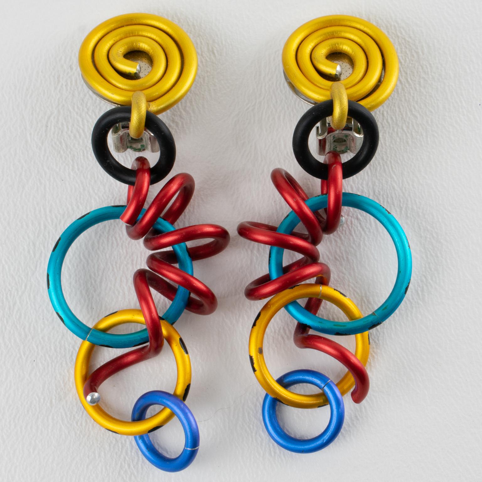 Estos magníficos pendientes de pinza colgantes firmados por David Spada, Nueva York, presentan un moderno diseño de la Era Espacial de los años 80 con elementos articulados en espiral colgantes y anillos de distintos tamaños. Son de metal de