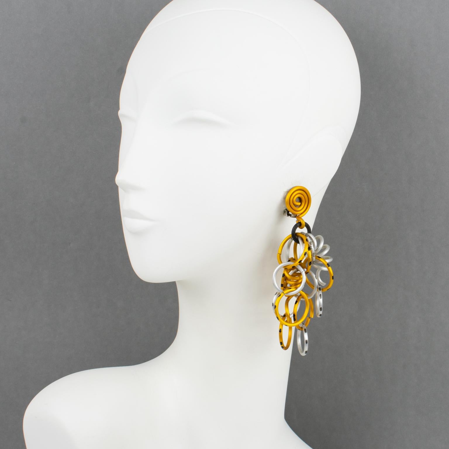 These spectacular David Spada, New York signed dangling clip-on earrings feature a trendy Space Age 1980s design with dangle articulated spirally coiled elements and assorted size rings. They are made of anodized aluminum metal with gold and silver