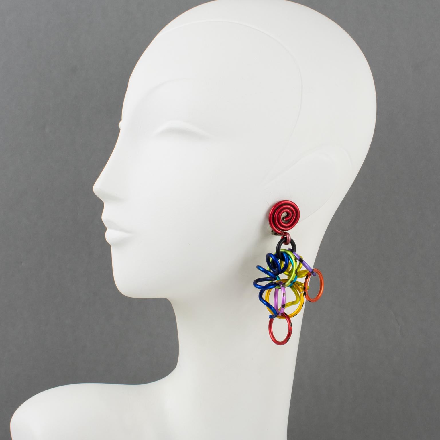 These incredible David Spada, New York signed dangling clip-on earrings feature a groovy Space Age 1980s design with dangle articulated spirally coiled elements with assorted size rings. They are made of anodized aluminum metal with bright rainbow