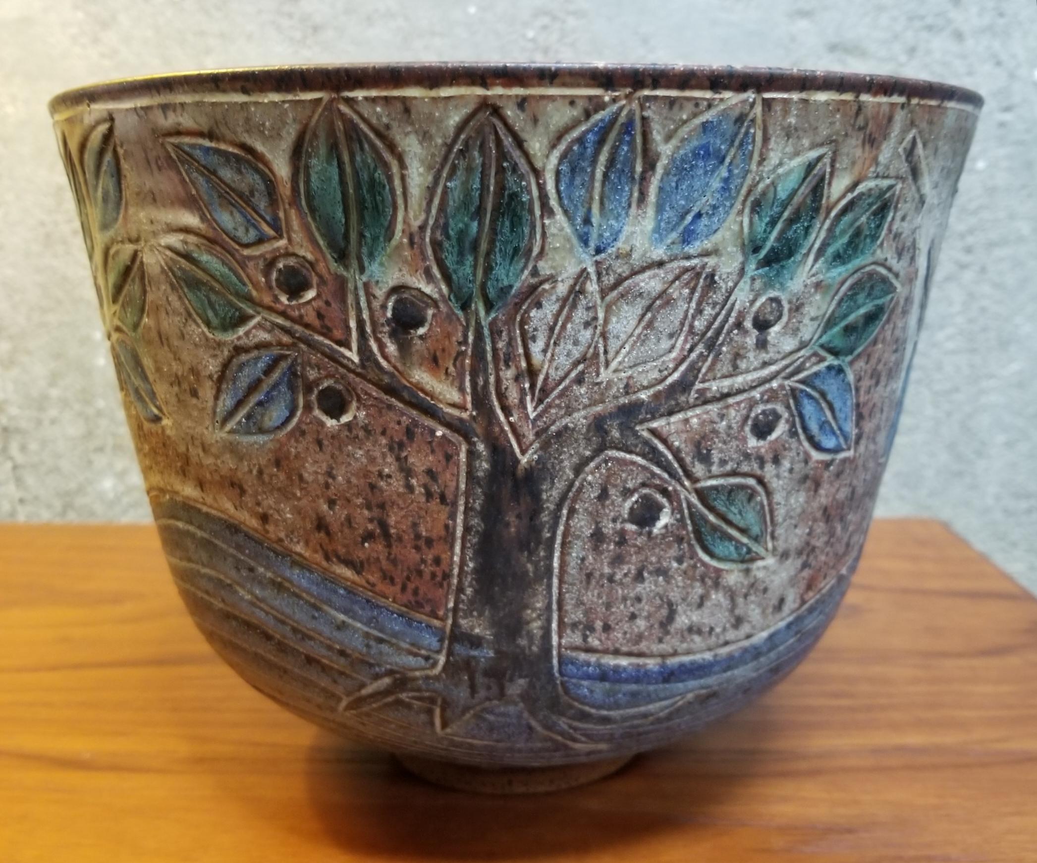 Beautiful glaze colors in this prolific California potter incised bowl. Hand turned and decorated with a figure, dragon and trees. Depicting Saint George and the Dragon. Circa late 1960's. Matt glaze on exterior, high-tone mottled glaze on interior.