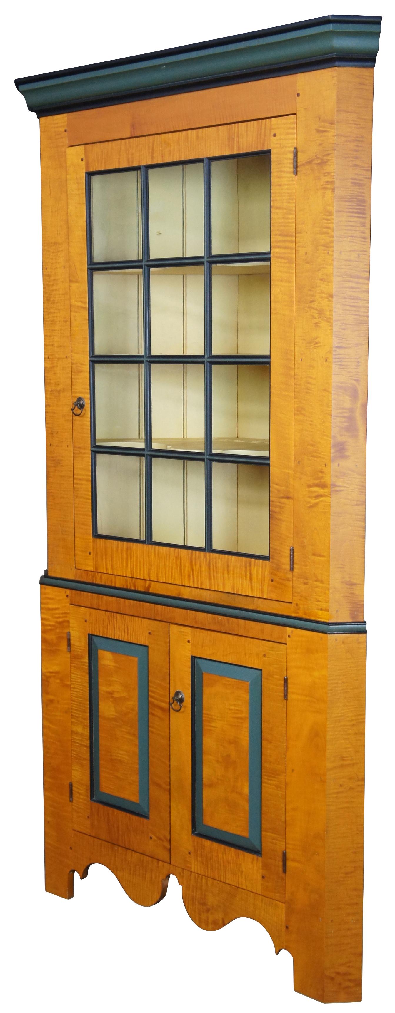 Curly maple corner cupboard by David T Smith, American, late 20th century. Constructed of curly maple with dark green trim, featuring four painted shelves in the upper eight paned glass cabinet and two shelves in the lower cabinet.

Measures: