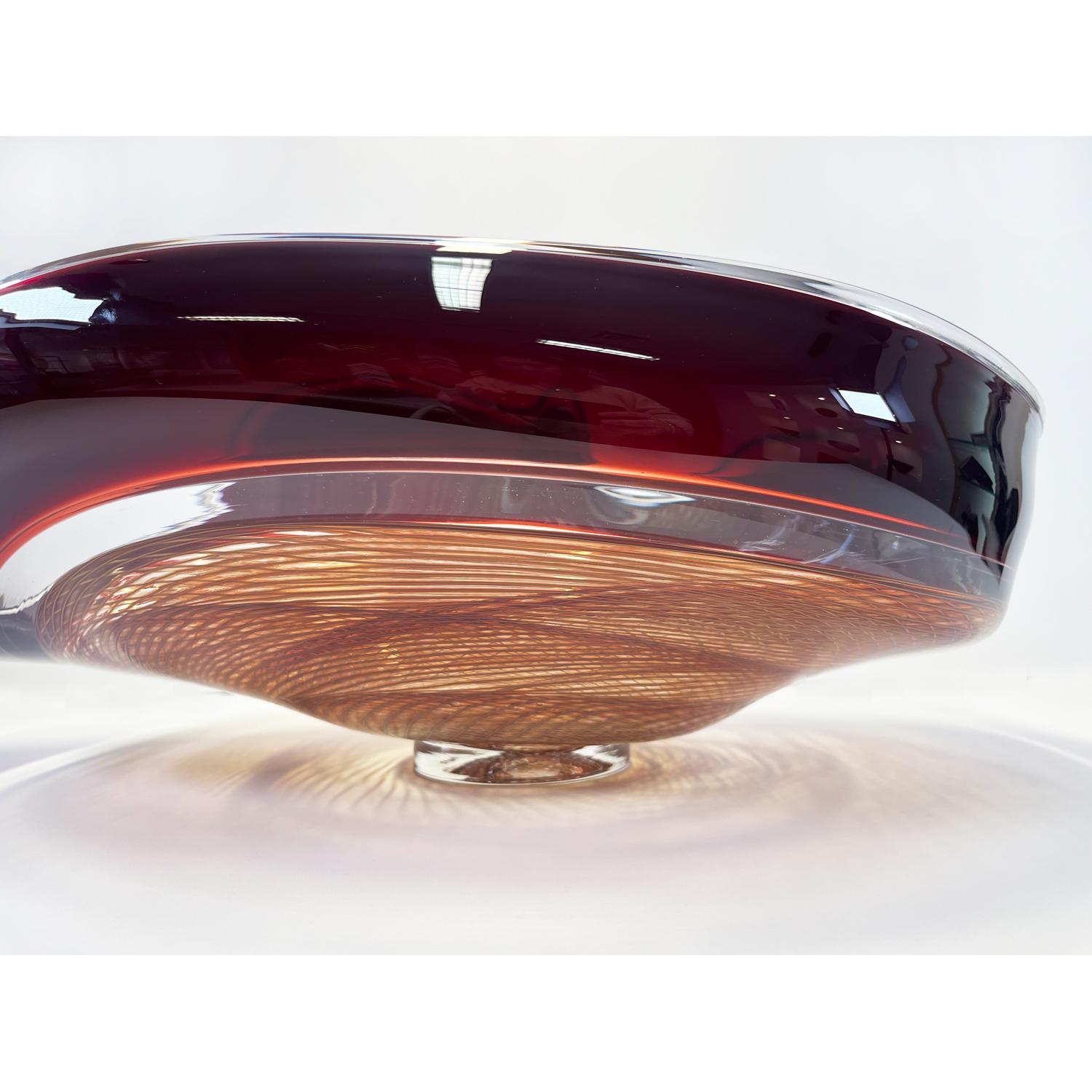 This Amber/Autumn Red Rondelle Bowl is a continuation of David's work with cane. Fusing his signature wave bowl motif with his newer rondelle cane pattern. This beautiful glass bowl is sure to be a showstopper in your space. 

David Thai is a