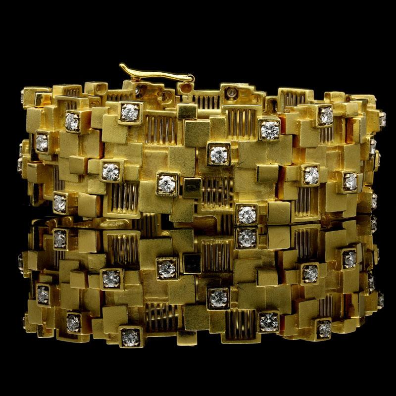 18 Carat gold signed David Thomas and with London assay marks
33 round brilliant diamonds

A modernist gold and diamond bracelet by David Thomas 1960, the wide asymmetric strap composed of multiple overlapping small square motifs in textured,