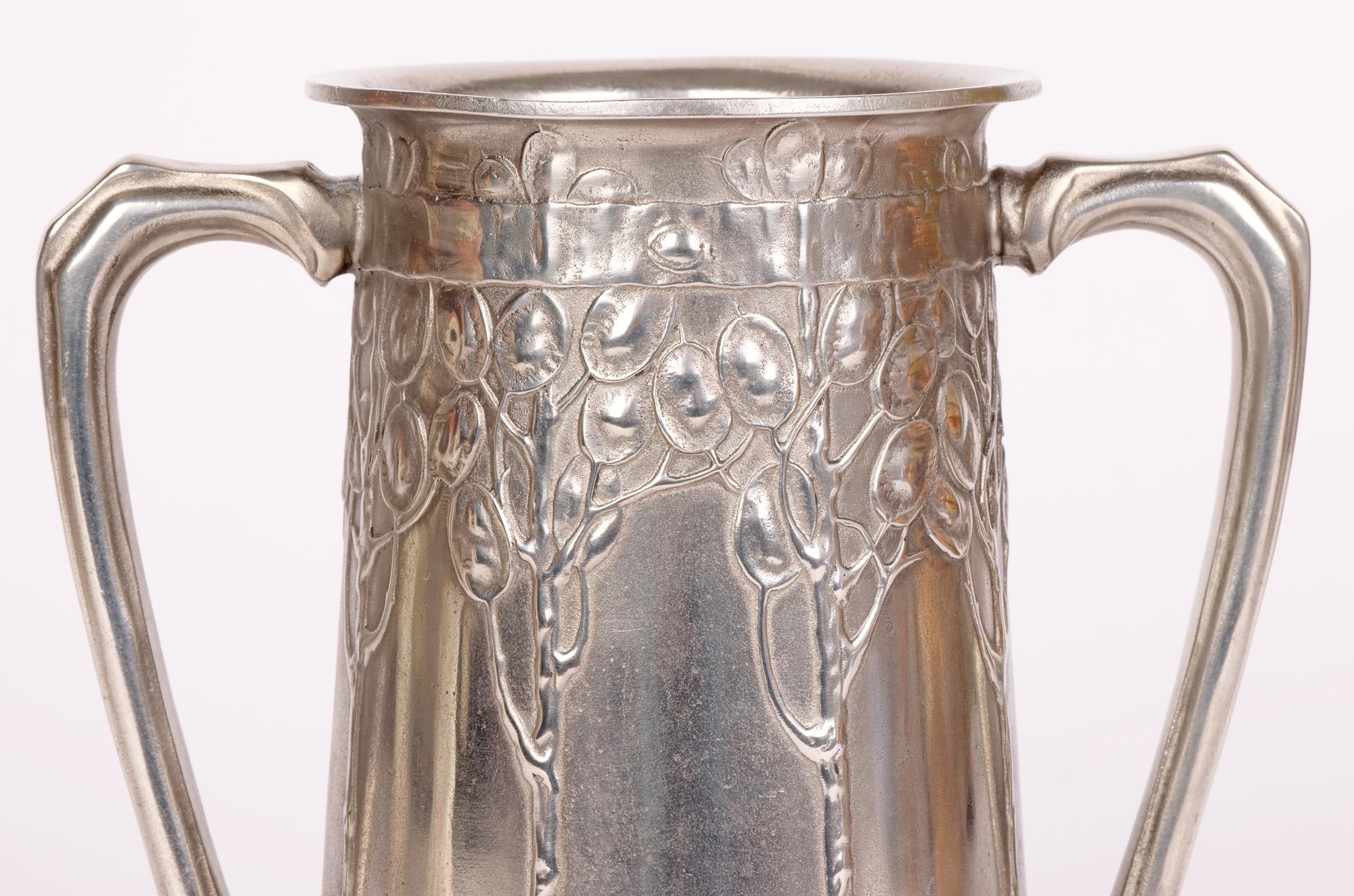 A stylish art nouveau Tudric pewter twin handled loving cup titled ‘FOR OLD TIMES SAKE’ designed by renowned designer David Veasey (British, active c.1900-1920) and dating from around 1902. 

This piece was produced by Liberty & Co and is of tall