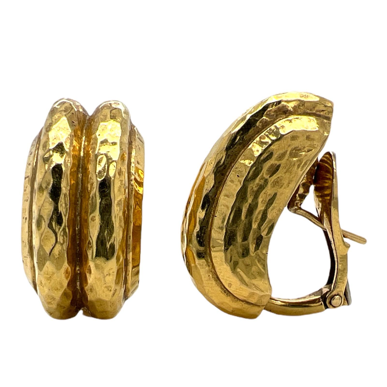 Authentic David Webb Half Hoop Earrings fashioned in 18 karat yellow gold. The earrings feature a hammered finish, lever-back posts, and measure .50 x 1.00 inches. 