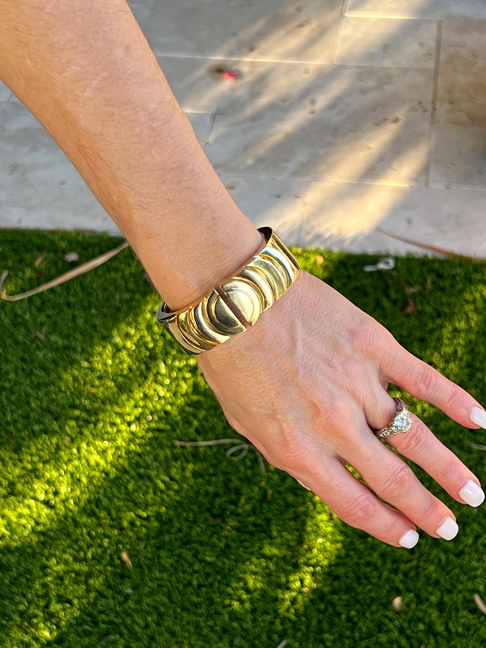 Modern David Webb hinged bangle bracelet fashioned in 18 karat yellow gold. The bracelet features circular endcaps and is hinged for easy wear. the bracelet measures 2.25 inches in internal diameter, .90 inches in width, and will fit 6.5 - 7.0 inch