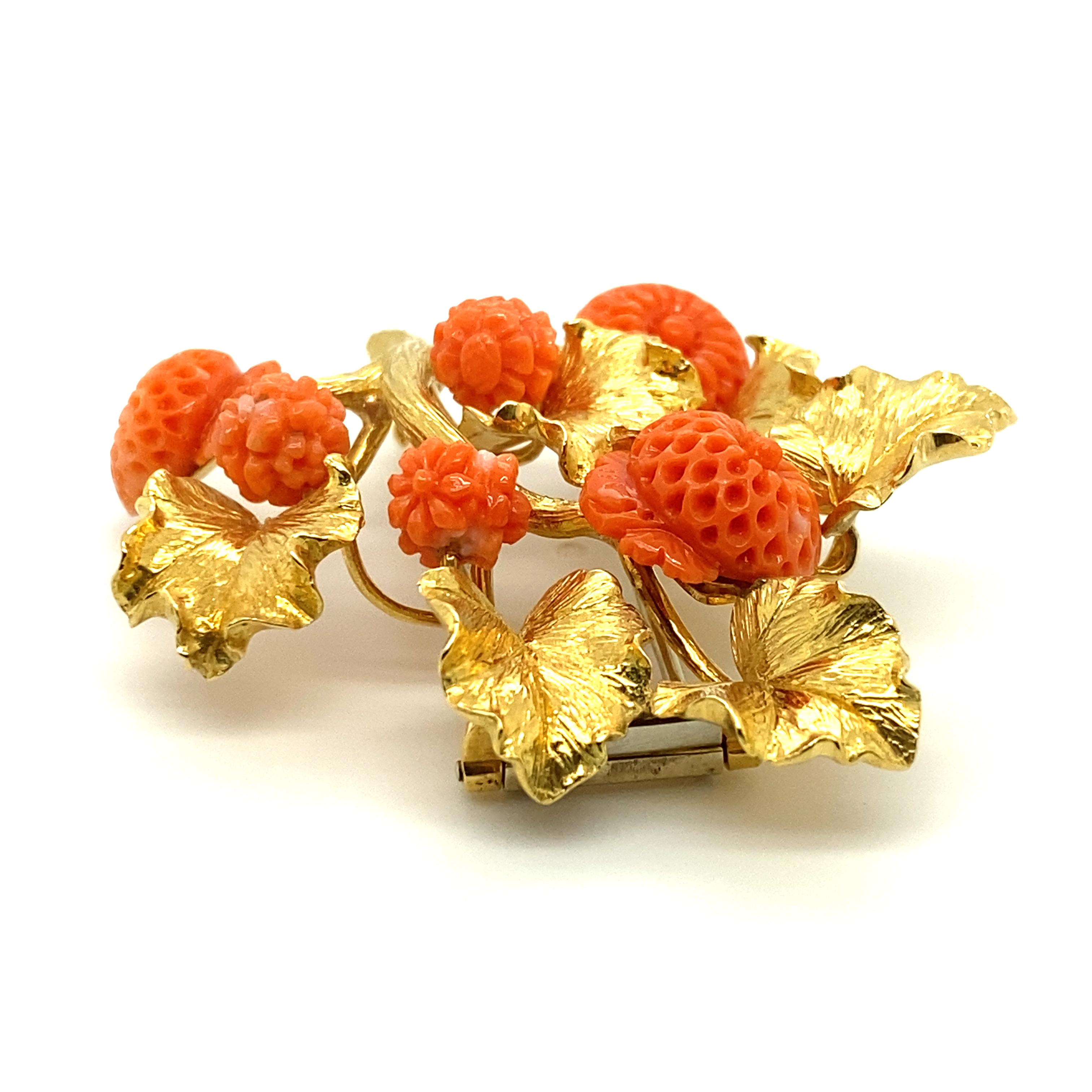 A vintage David Webb 18k gold and carved coral brooch featuring coral carved in exacting detail by hand into budding and blooming flowers, with gold leaves textured to resemble living, three-dimensional leaves.

Stamped David Webb, Webb, 18k.