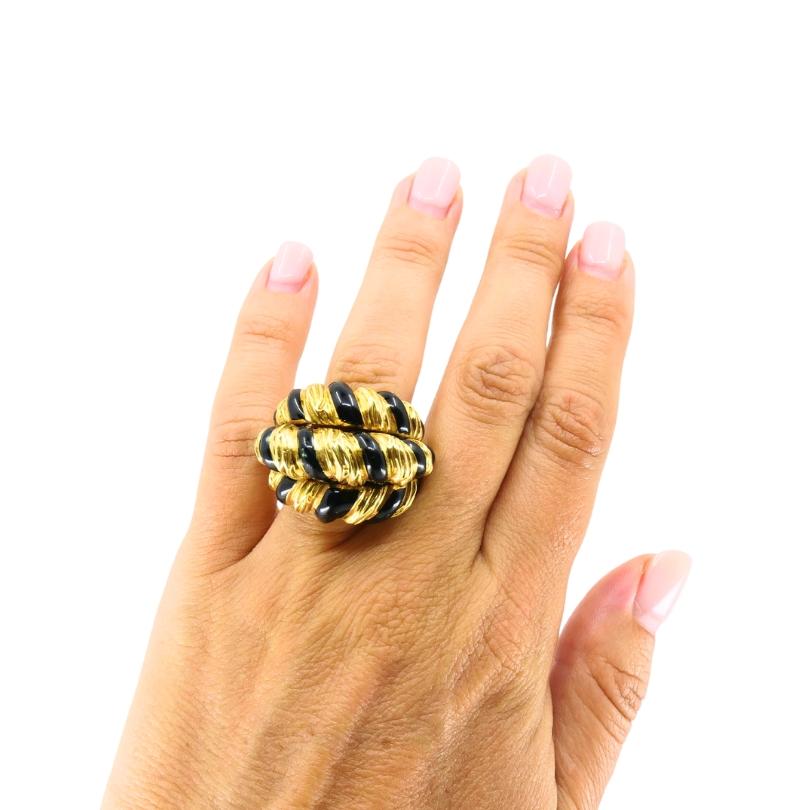 
Bold and sculptural, this David Webb cocktail ring is crafted in 18k gold and features a dimensional dome design with alternating rows of gleaming gold and glossy black enamel. The ridged, fluted gold work is emblematic of Webb’s signature