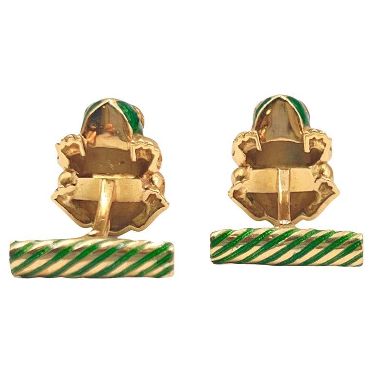 Whimsical frog motif cufflinks by David Webb in 18k yellow gold. Green enamel on the body with striped green enamel inlay on the swivel bar.  The eyes are bezel set with four oval, cabochon cut, rubies measuring approximately 2-3mm each.  Signed