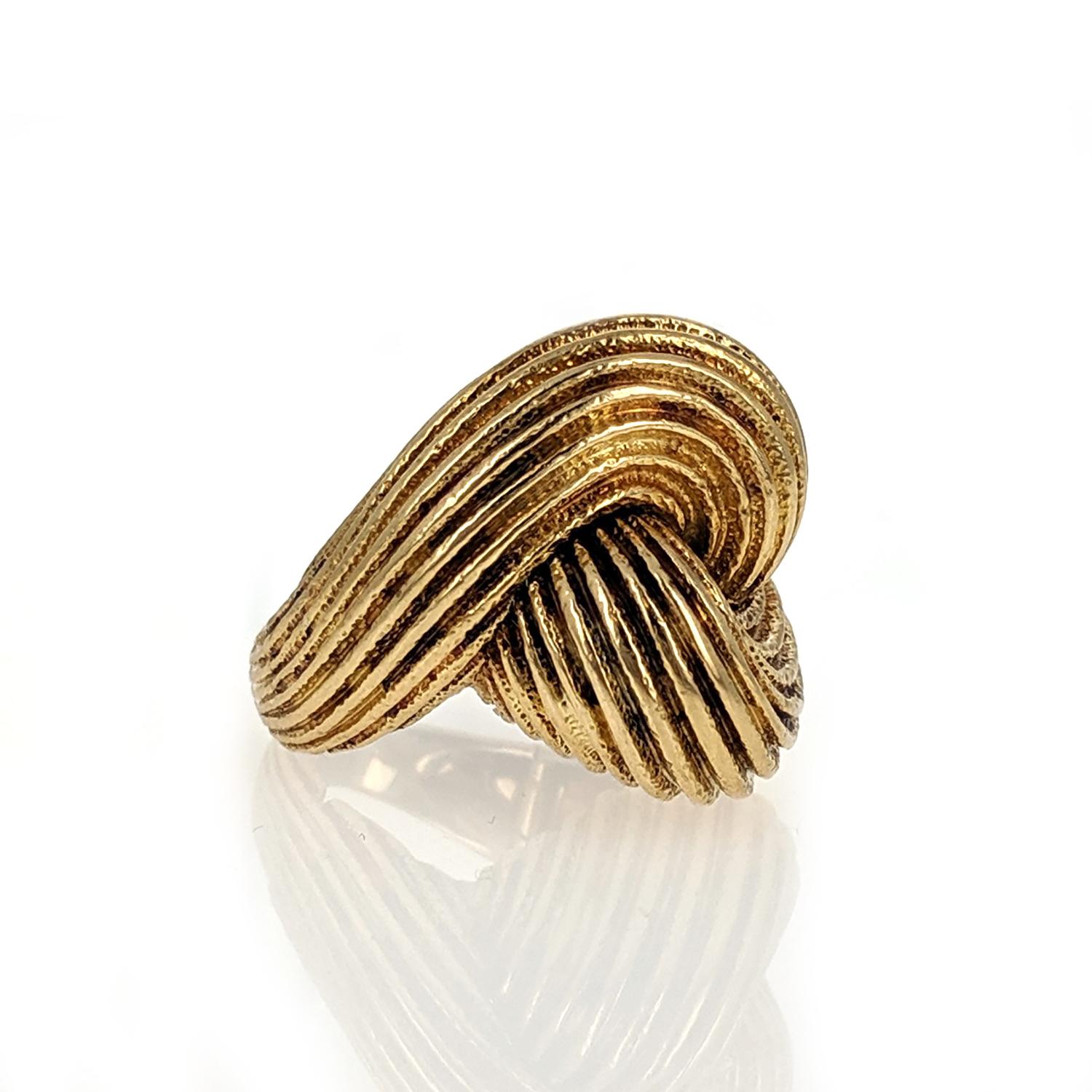 A voluptuously organic knot form in fluted 18k yellow gold. Signed Webb for David Webb. 
A very secure deployment clasp was incorporated into the design to likely accommodate a larger knuckle. Considering the ring carries its weight on the knot