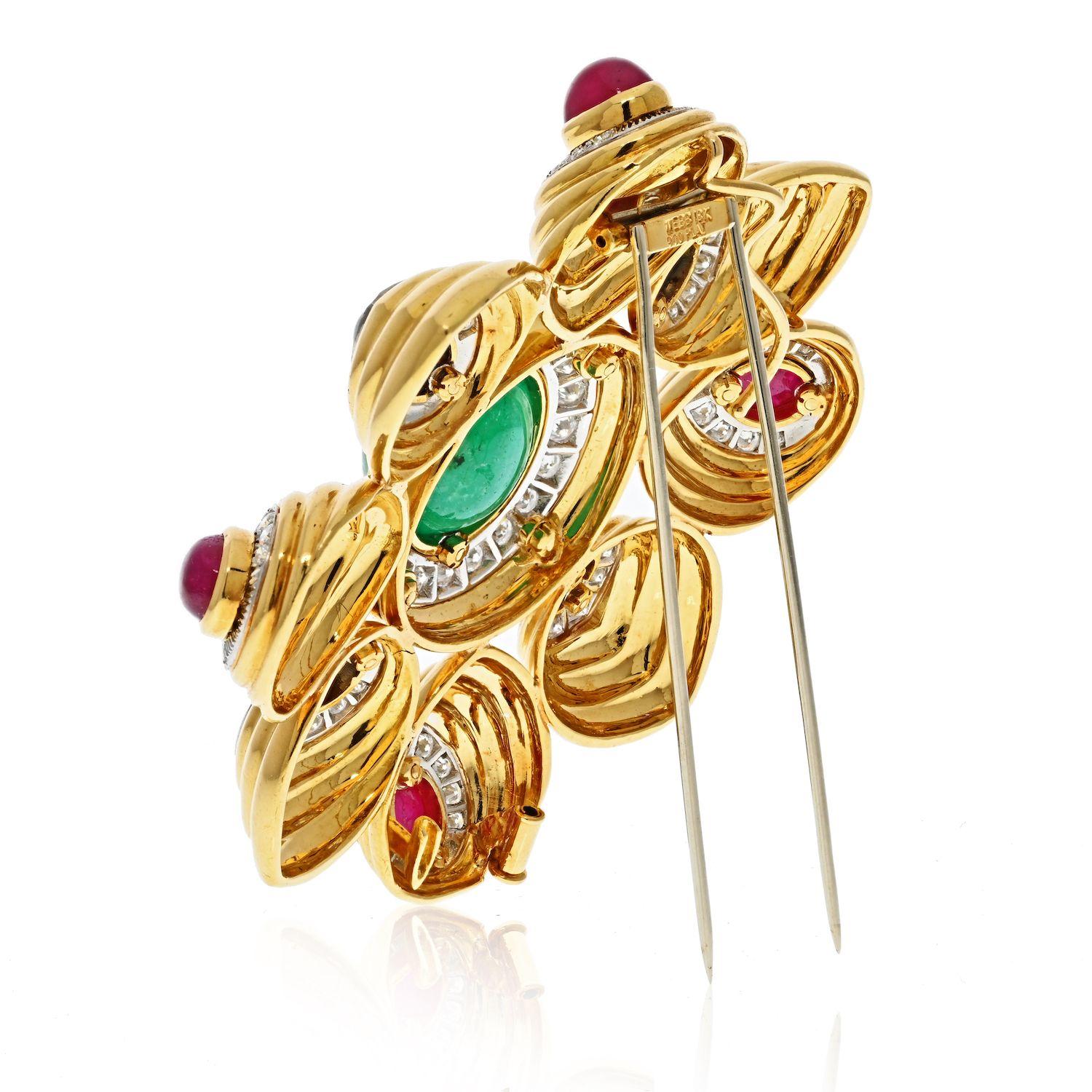 A substantial 18k yellow gold eight pointed combination brooch/pendant with a large center cabochon emerald, and four each of smaller cabochon blue sapphires and cabochon rubies. Brilliant round diamond pave style borders surround each
