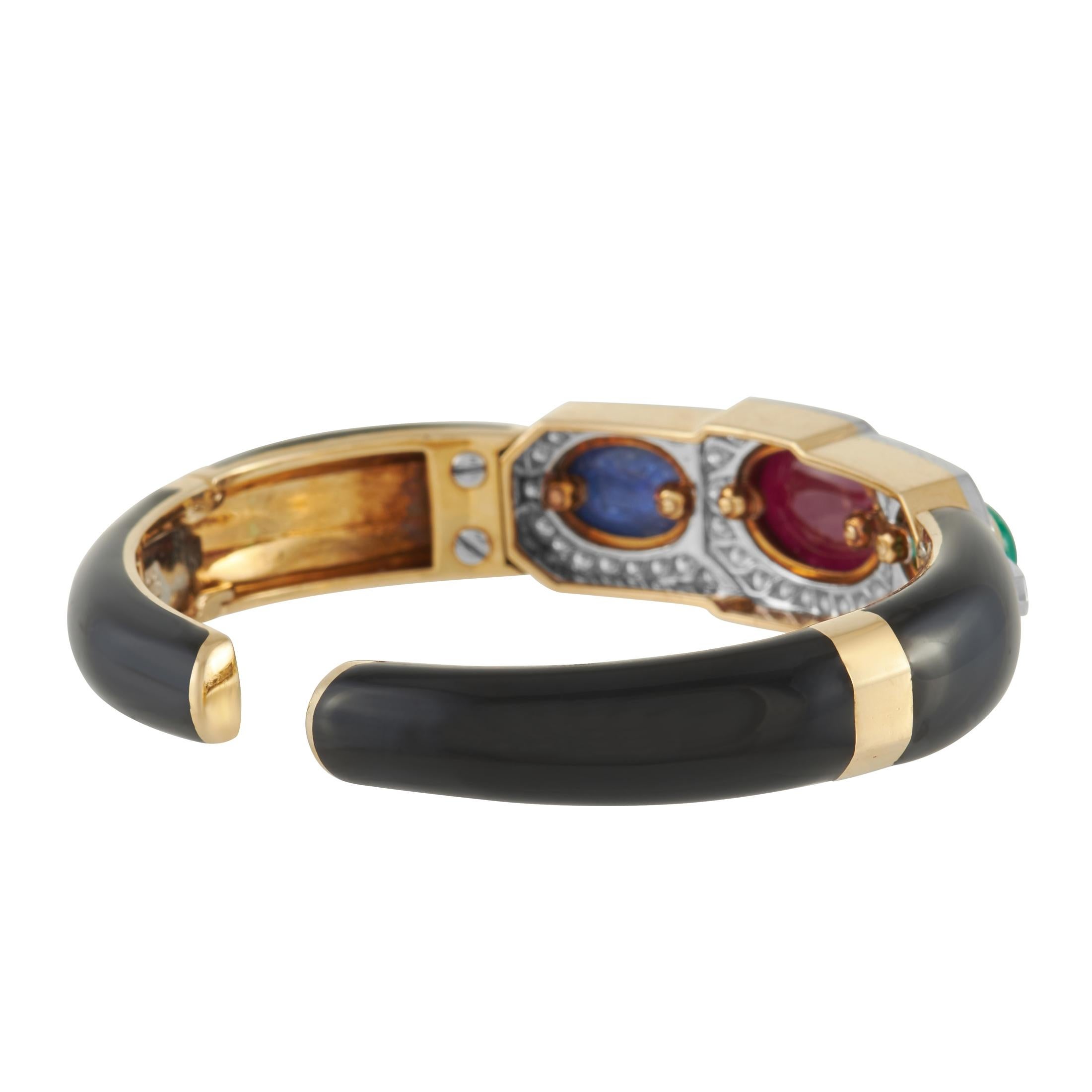 An array of colors make this David Webb bracelet a showpiece that will continually capture your imagination. Black enamel accents this 6.3” bangle-style bracelet, which in anchored by an 18K Yellow Gold base. At the center, you’ll find a trio of