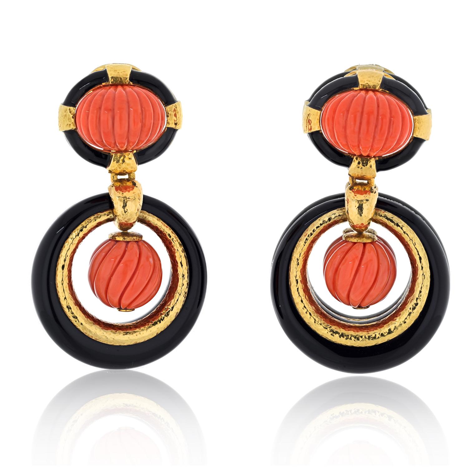 The David Webb Platinum & 18K Yellow Gold Carved Coral Onyx Door Knockers Earrings are a remarkable testament to the designer's distinctive artistry. Crafted with a keen eye for detail, these earrings harmoniously blend carved coral, onyx, and 18K