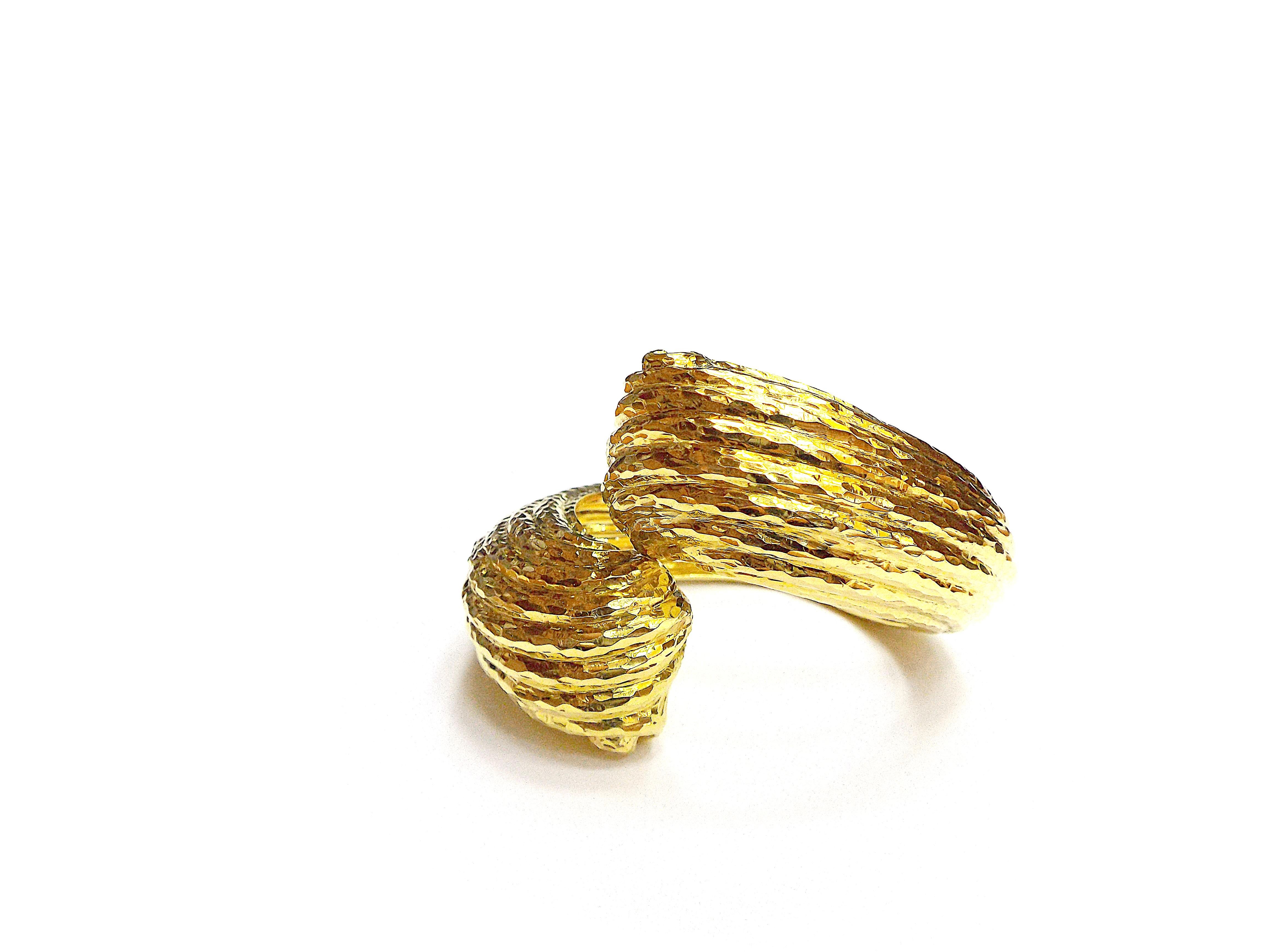 An elegant chunky cuff bracelet by David Webb made of 18k yellow gold. Of hinged crossover design with a hammered finish; signed David Webb, marked 18K; inner circumference 6 in.
