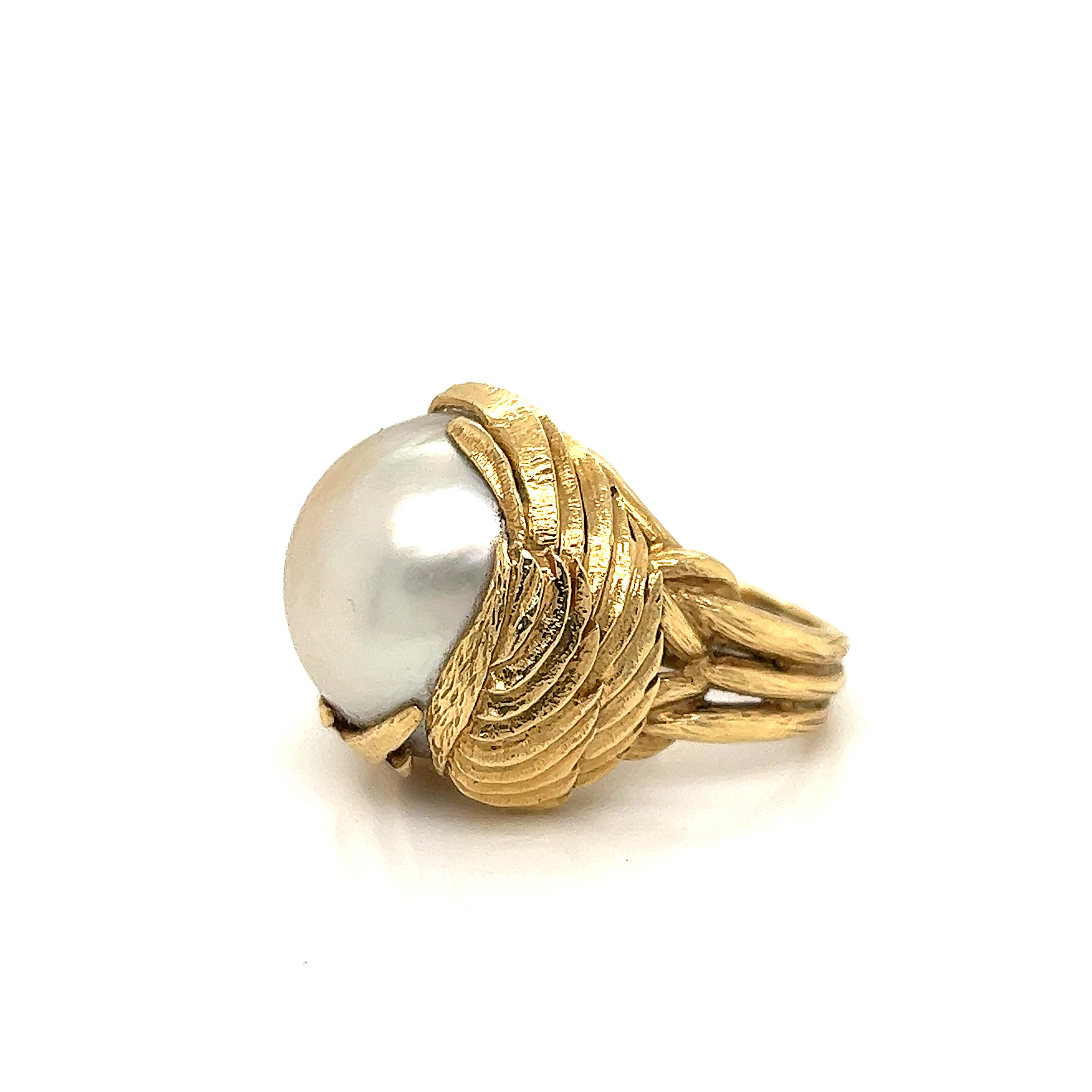 A beautiful creation from famed designer David Webb. This unique design is crafted in 18K yellow gold and shows a mabe pearl set in the center as the focal point. The mabe pearl measures approximately 20 x 20 millimeters and is nestled in the 18K