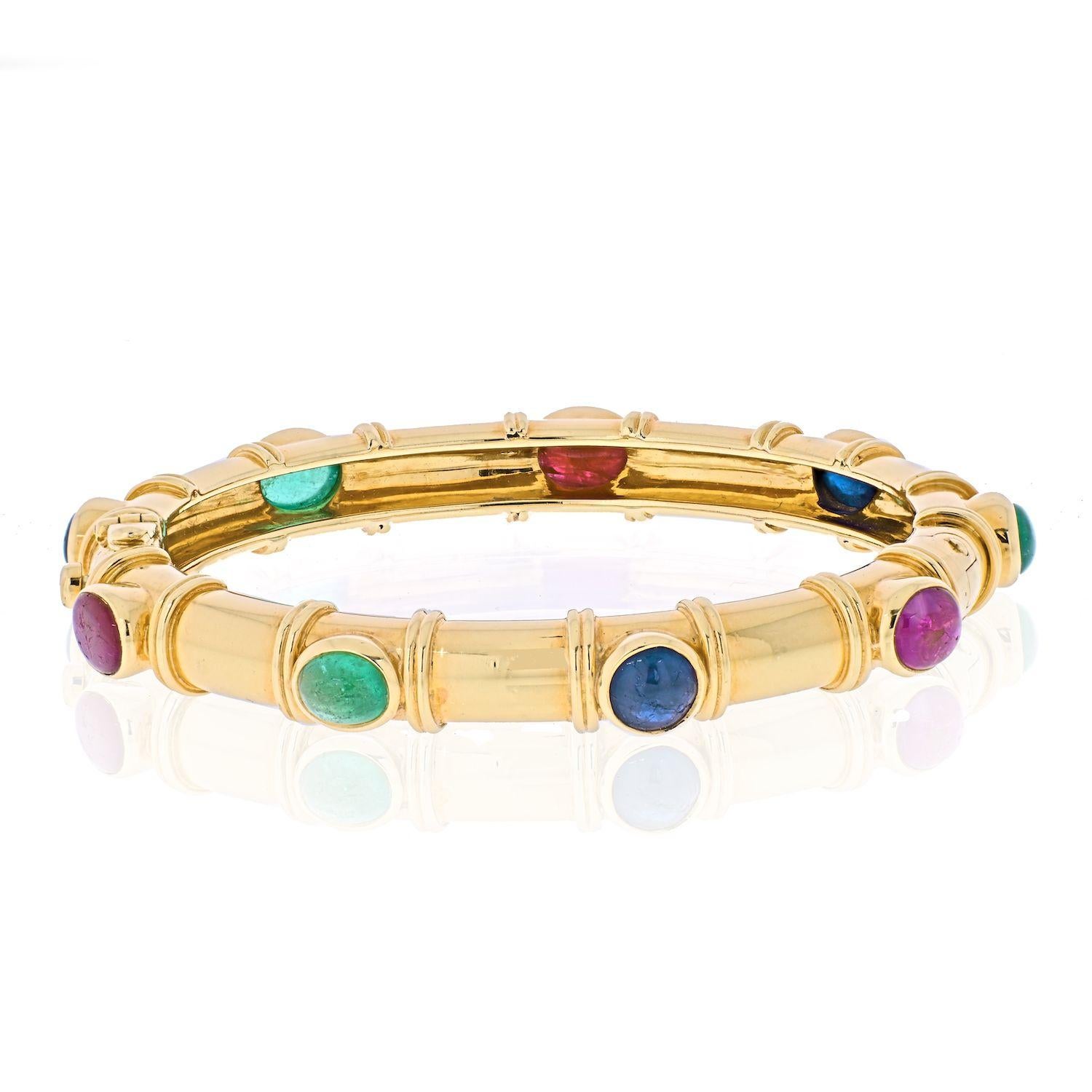 This yellow gold David Webb gemstone bangle bracelet is set with nine oval cut cabochon rubies, sapphires and emeralds. Designed with a hinged lock for easy wear it is elegant and minimalist, combined with pop of color making this bangle appear