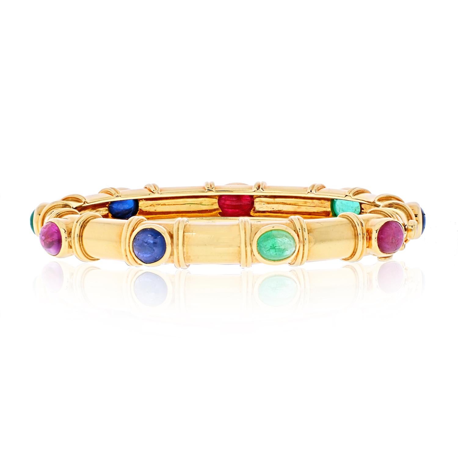 18K yellow gold David Webb gemstone ladies bangle bracelet. This piece is set with nine multi colored gemstones, oval cut cabochon rubies, sapphires and emeralds. Designed with a hinged lock for easy wear it is elegant and minimalist, combined with