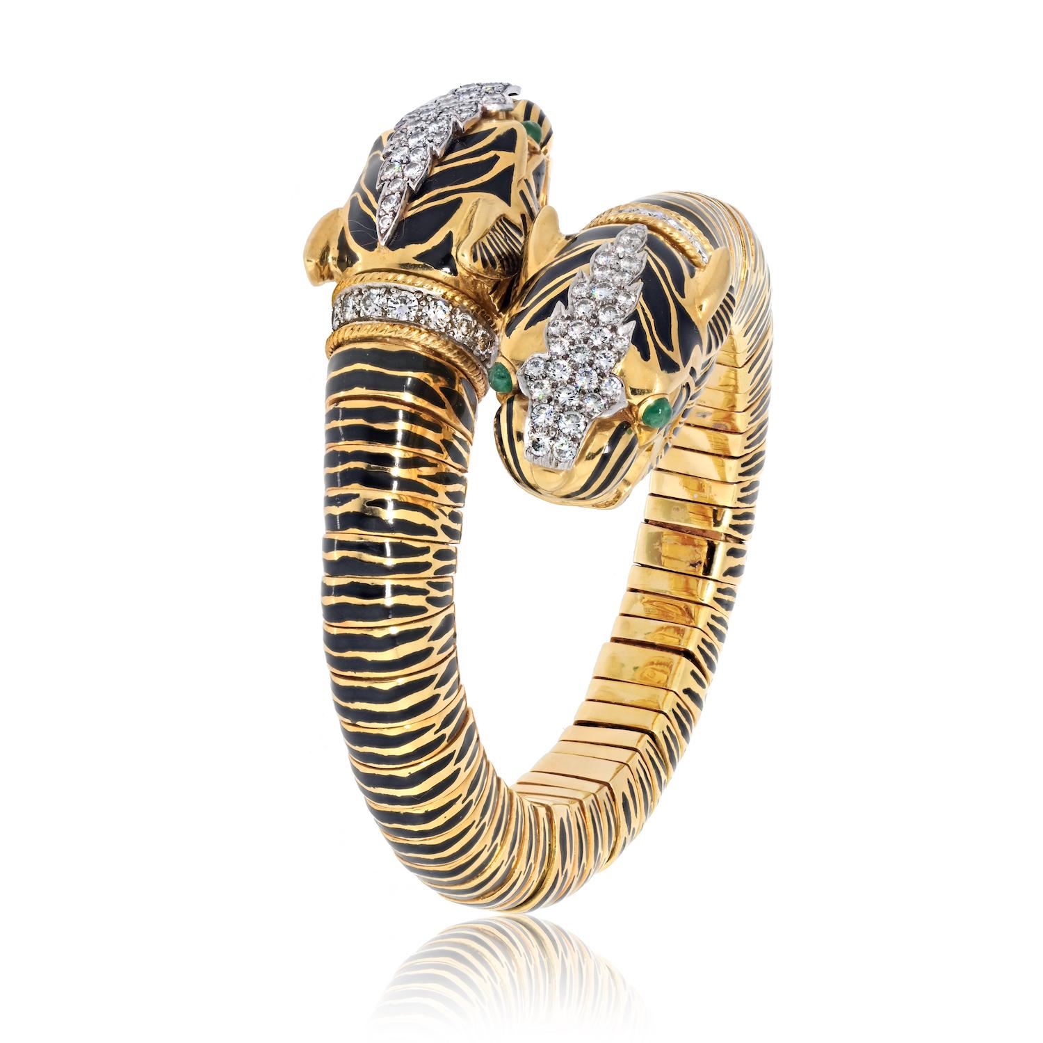Embrace the wild elegance of the David Webb Kingdom Collection with this remarkable double-tiger head bracelet. Crafted in lustrous 18k yellow gold, the bangle features striking black enamel stripes that add depth and character to the design. The
