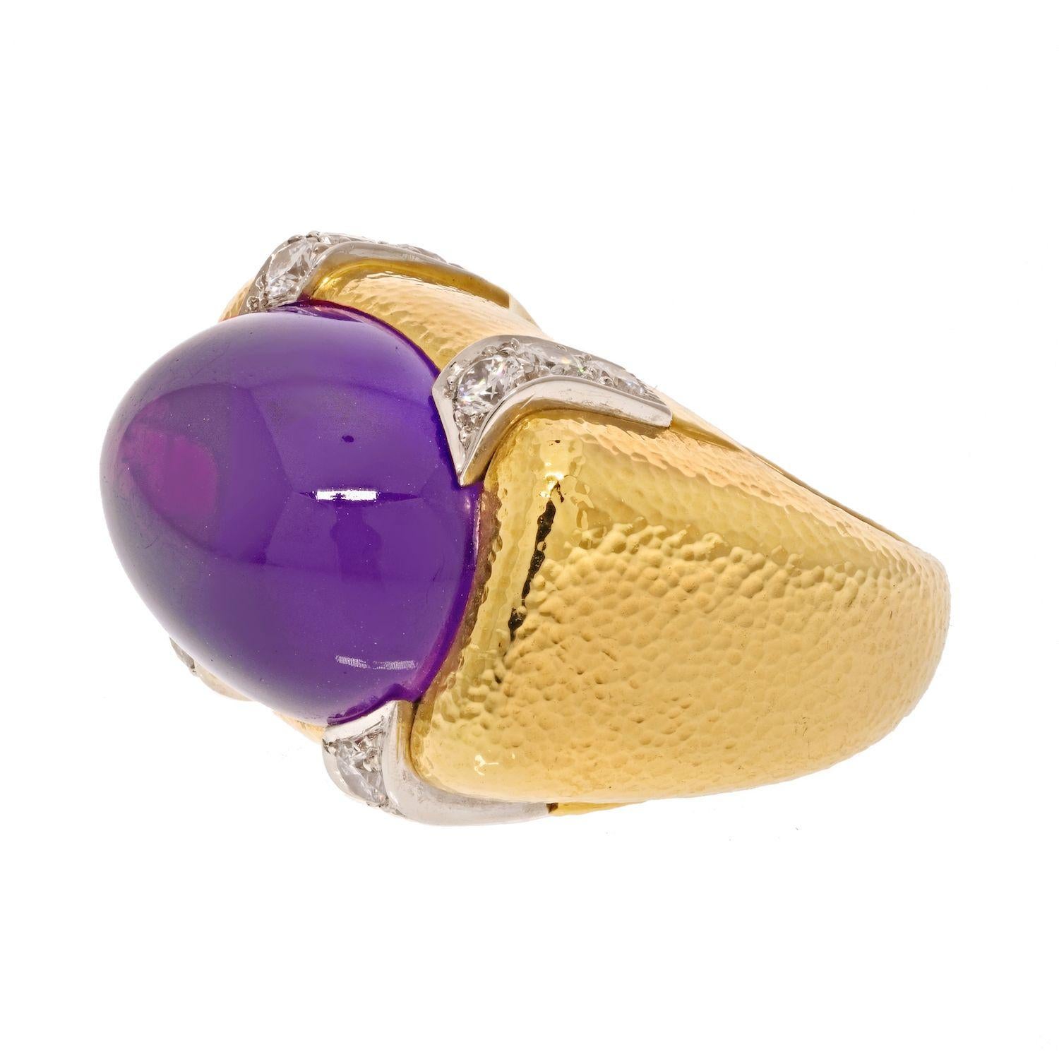 David Webb Platinum & 18K Yellow Gold Cabochon Amethyst And Diamond Cocktail Ring.

Centering a large cabochon amethyst mounted East to West held by the bezel, accented with round cut diamonds in four corners. Vibrant purple color of amethyst,