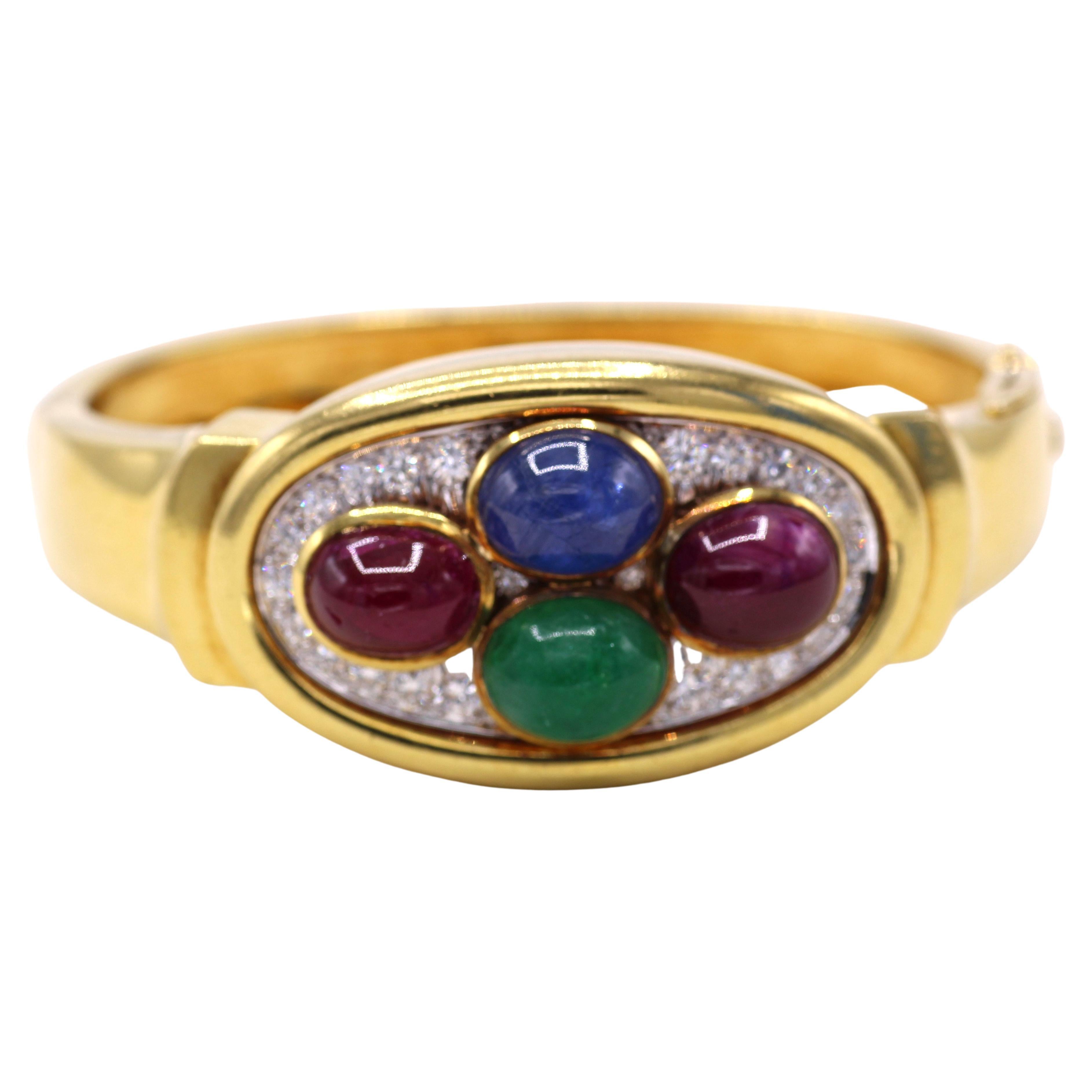 Beautifully designed and masterfully handcrafted, this bangle bracelet by David Webb from ca 1980 displays a fun and colorful array of gemstones worked in platinum and 18 karat yellow gold. 2 cabochon rubies, 1 cabochon sapphire and 1 cabochon
