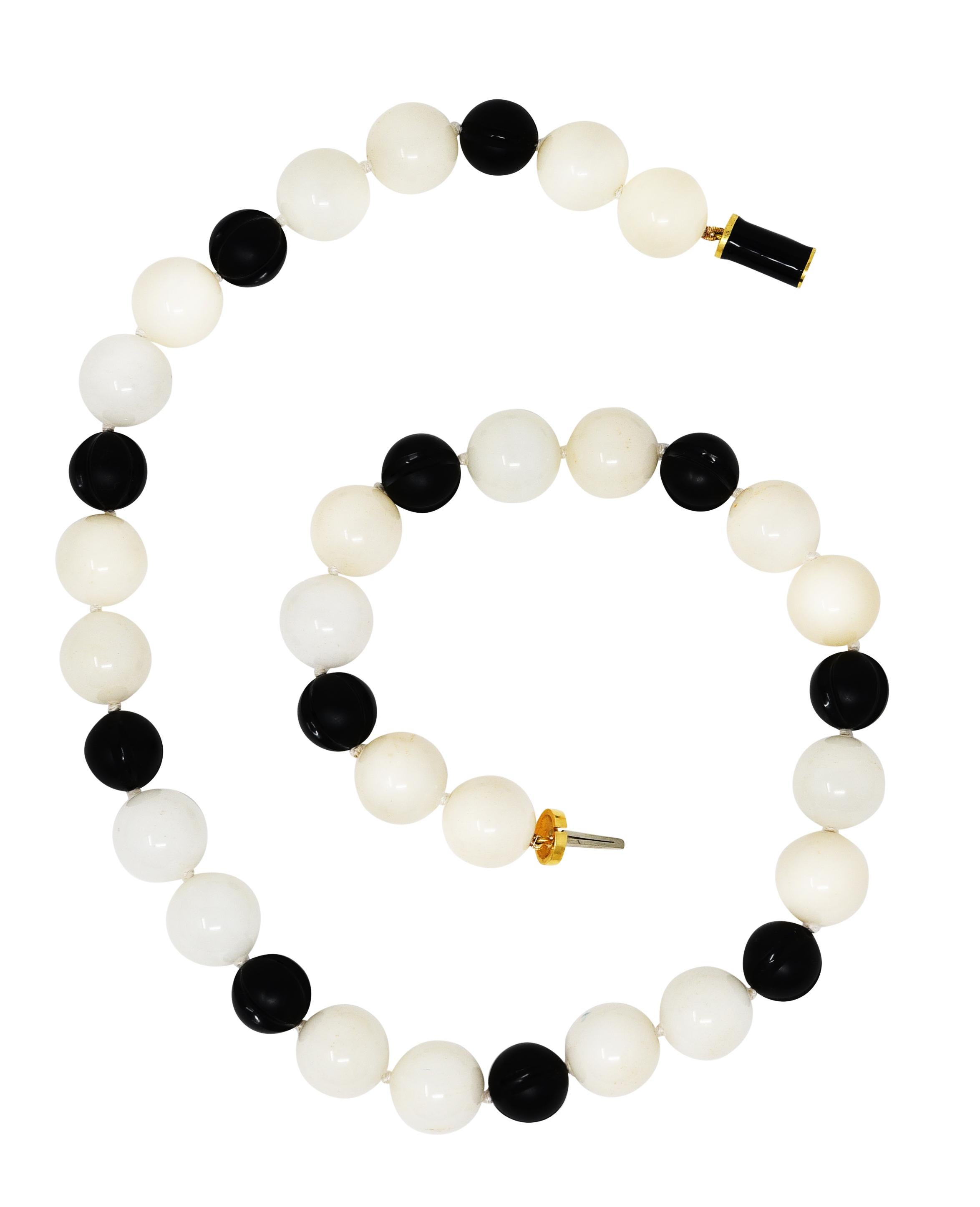 Necklace is comprised of onyx and rock crystal quartz round beads strung on knotted silk cord. Onyx beads are 13.0 mm round - opaque matte black in color with polished carved linear grooves. Rock crystal quartz are 16.0 mm round - translucent cream