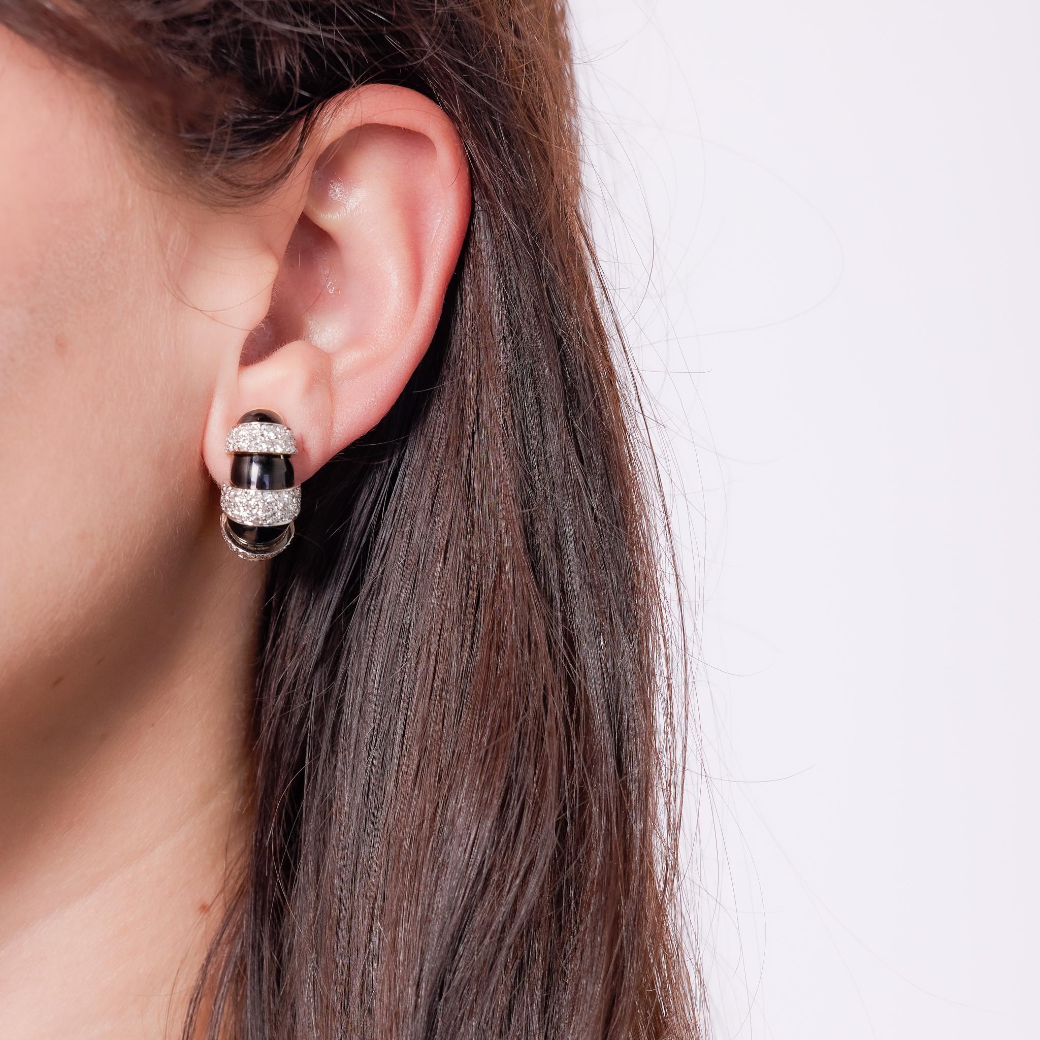 Crafted in the 1970s, these Mid Century earrings by David Webb are a bold display of elegance and craftsmanship. Made in 18k yellow gold with platinum and black enamel accents, they feature 94 round brilliant cut diamonds totaling approximately 3.30