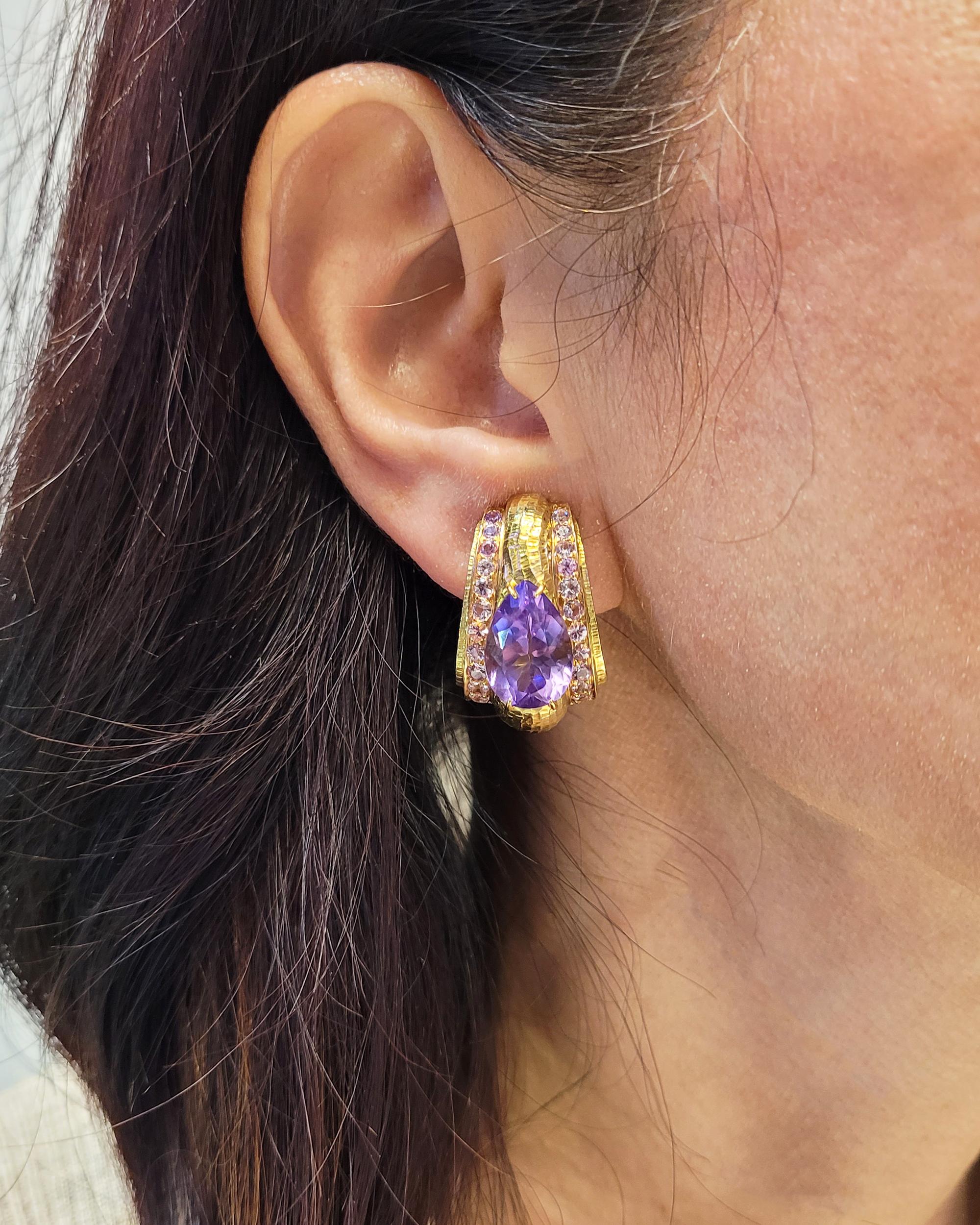 A pair of ear clips made by David Webb.
Featuring two pear-shape amethysts and round pink sapphires.
Mounted in 18k yellow gold with hammered finish. 
Signed David Webb.
Gross weight is 34.07 gr.
Clip-on style.