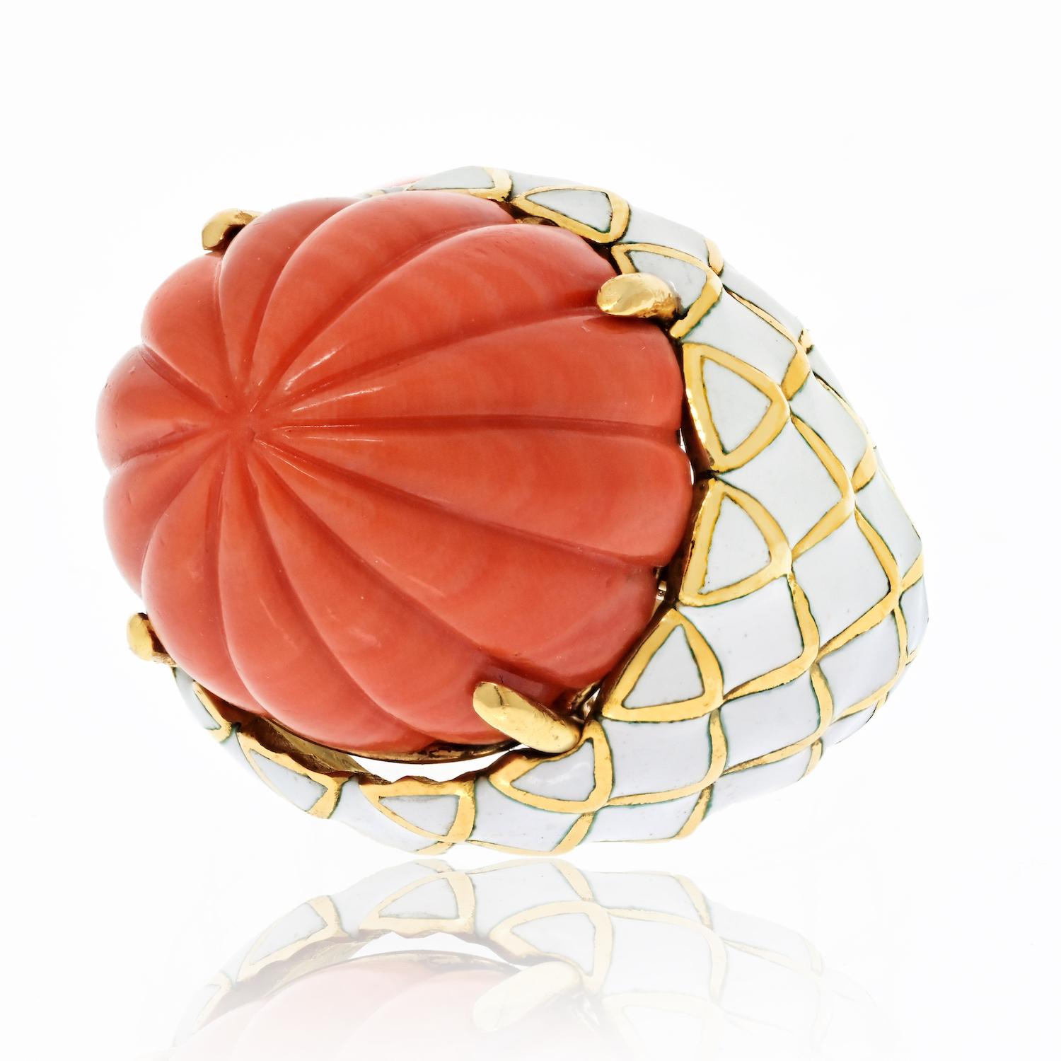 The 18k yellow gold ring by David Webb is a striking and unique piece of jewelry that showcases the exceptional craftsmanship and attention to detail for which the David Webb brand is known. This ring features a carved coral stone in the center,