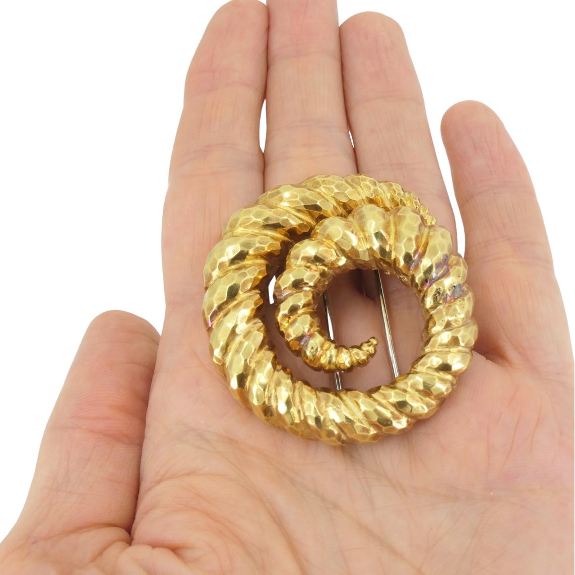Questa spilla vintage in oro 18k di David Webb mostra lo stile audace e scultoreo per cui la casa è nota. Disegnata a forma di spirale, la spilla presenta una finitura martellata che conferisce all'oro una superficie vivace e dimensionale, mentre le