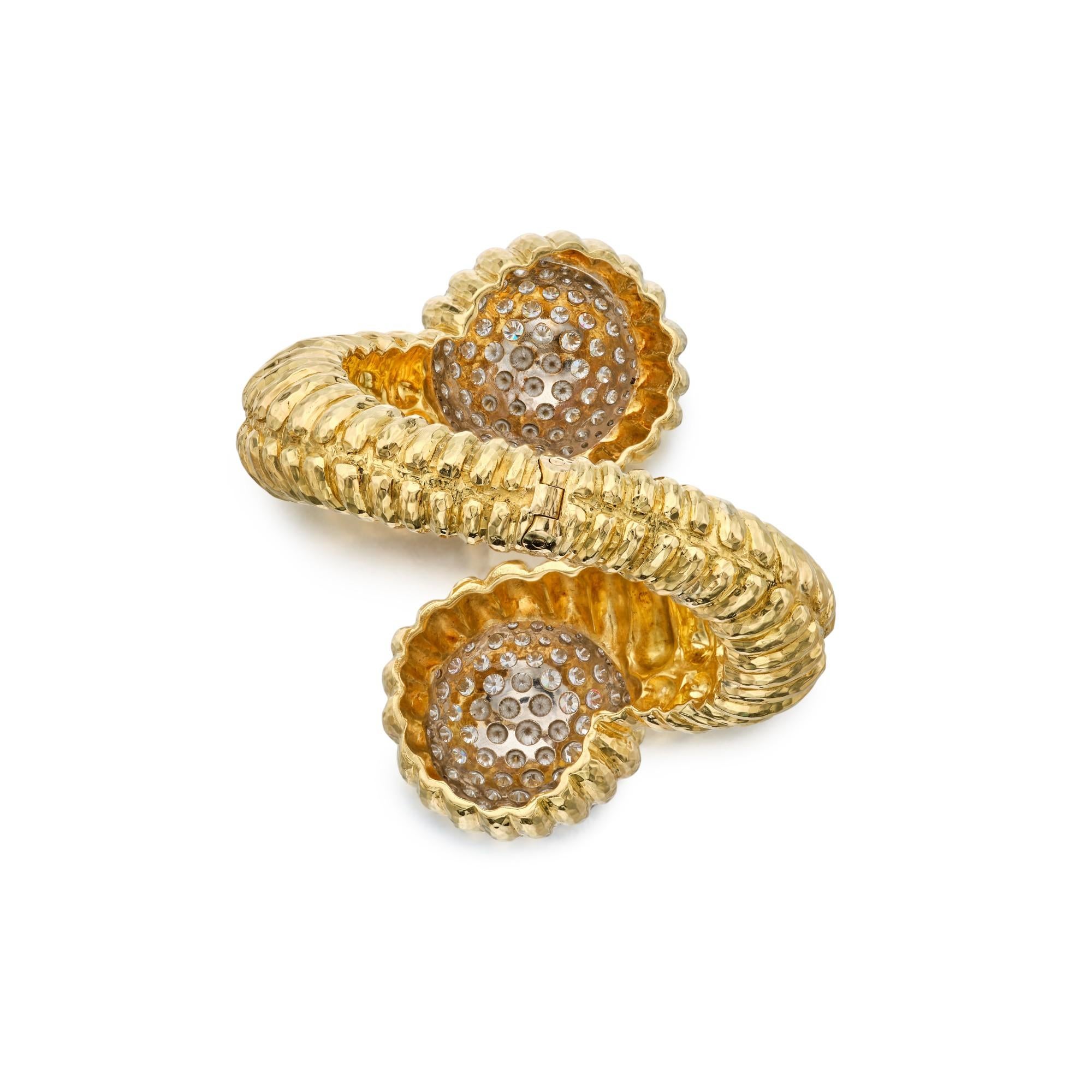 1960's David Webb Diamond and Gold Bracelet This bracelet has a bypass design composed of fluted
hammered 18k yellow gold. Each end of the bracelet accented with with round brilliant diamonds with a total carat weight of approximately 24 carat,