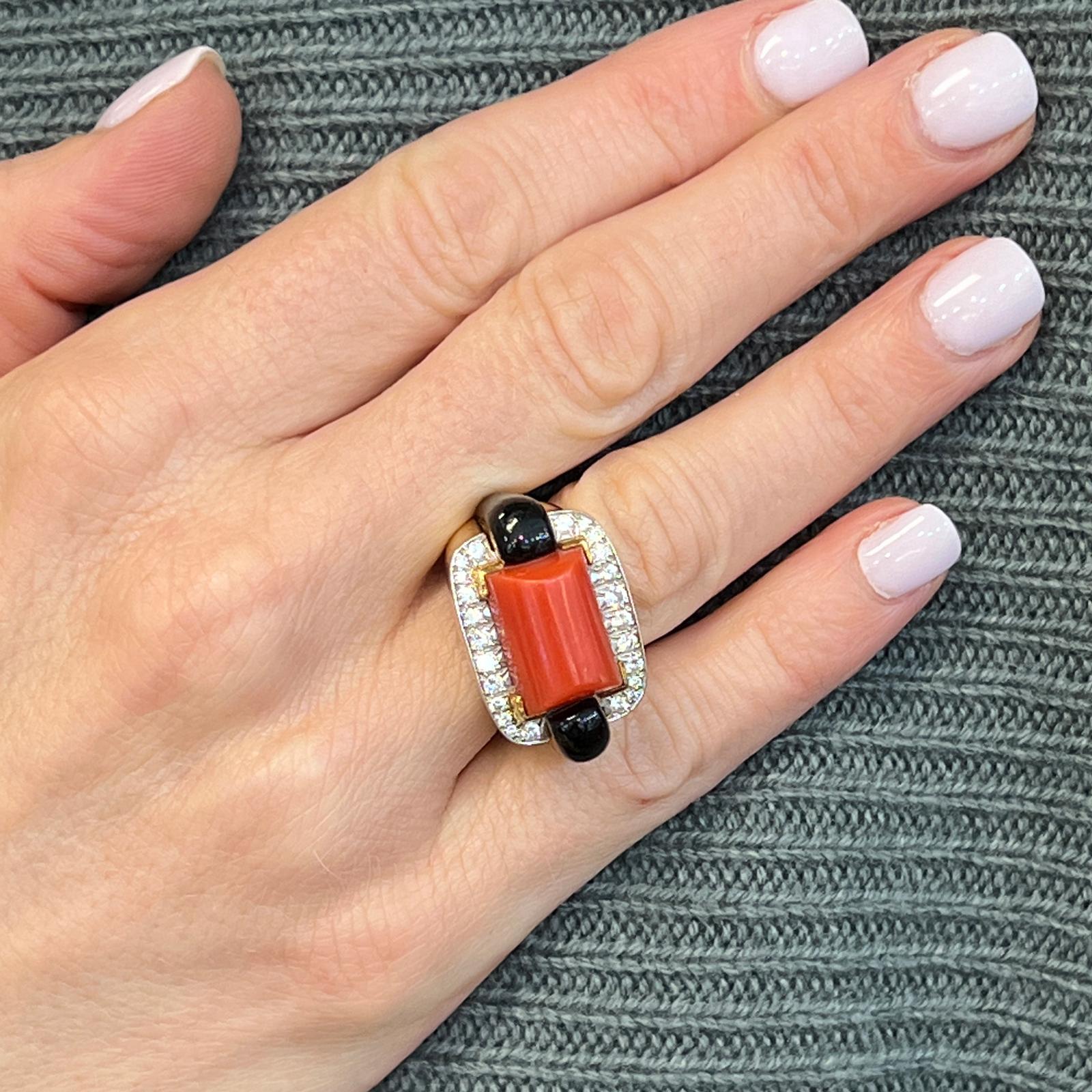 Fabulous David Webb cocktail ring fashioned in 18 karat yellow gold and platinum. The ring features onyx, coral, and 24 round brilliant cut diamonds weighing approximately 1.00 CTW and graded G color VS1 clarity. The ring is size 6, measures 16mm in