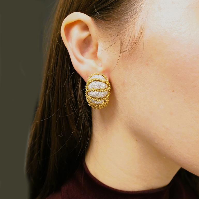 A magnificent pair of diamond earrings by David Webb in 18k gold.
Designed as huggie earrings with clip-on closure, they were crafted by using metal granulation technique. Multiple gold droplets were staged in the graduated horizontal rows to shape