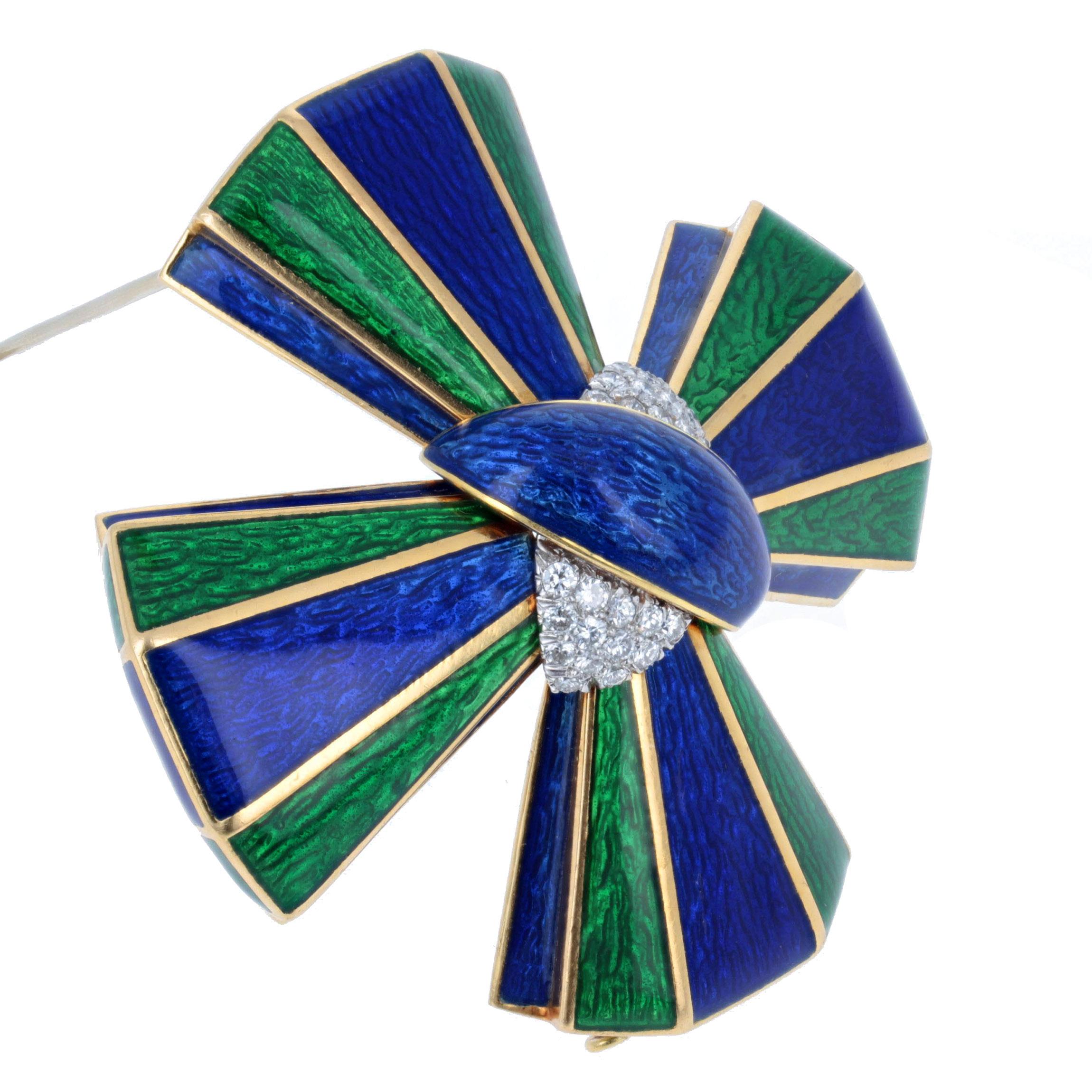 This bold brooch is designed as a Maltese cross with a vivid and translucent combination of emerald green and royal blue enamel alternating throughout and centering upon a knot of the same blue enamel and pave set diamonds that weigh approximately