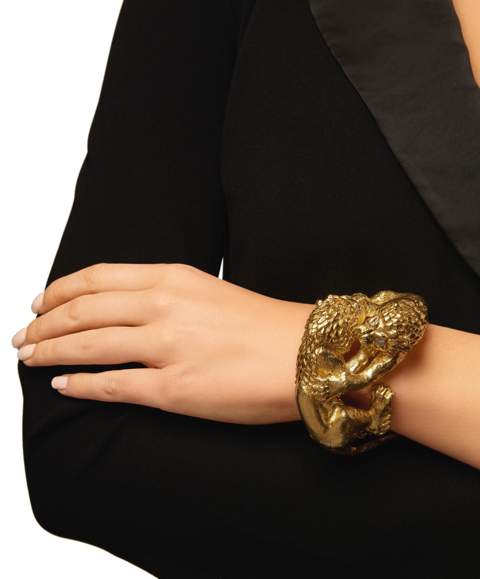 A statement cuff bracelet by David Webb featuring textured gold two lions in battle, with pear-shaped diamond eyes. Internal circumference 6½ inches.
