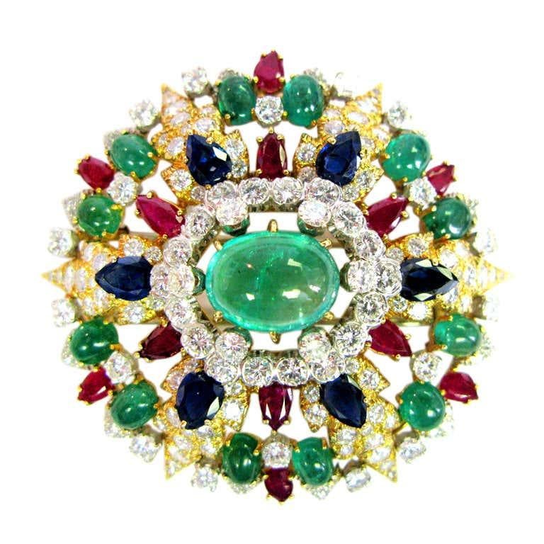 Diamonds, cabochon emeralds, rubies, and blue sapphires make this 18kt gold and platinum David Webb signed piece a must-have. The iridescent center stone is sure to catch eyes, but the entire broach is colorful and made with beautiful gems that will