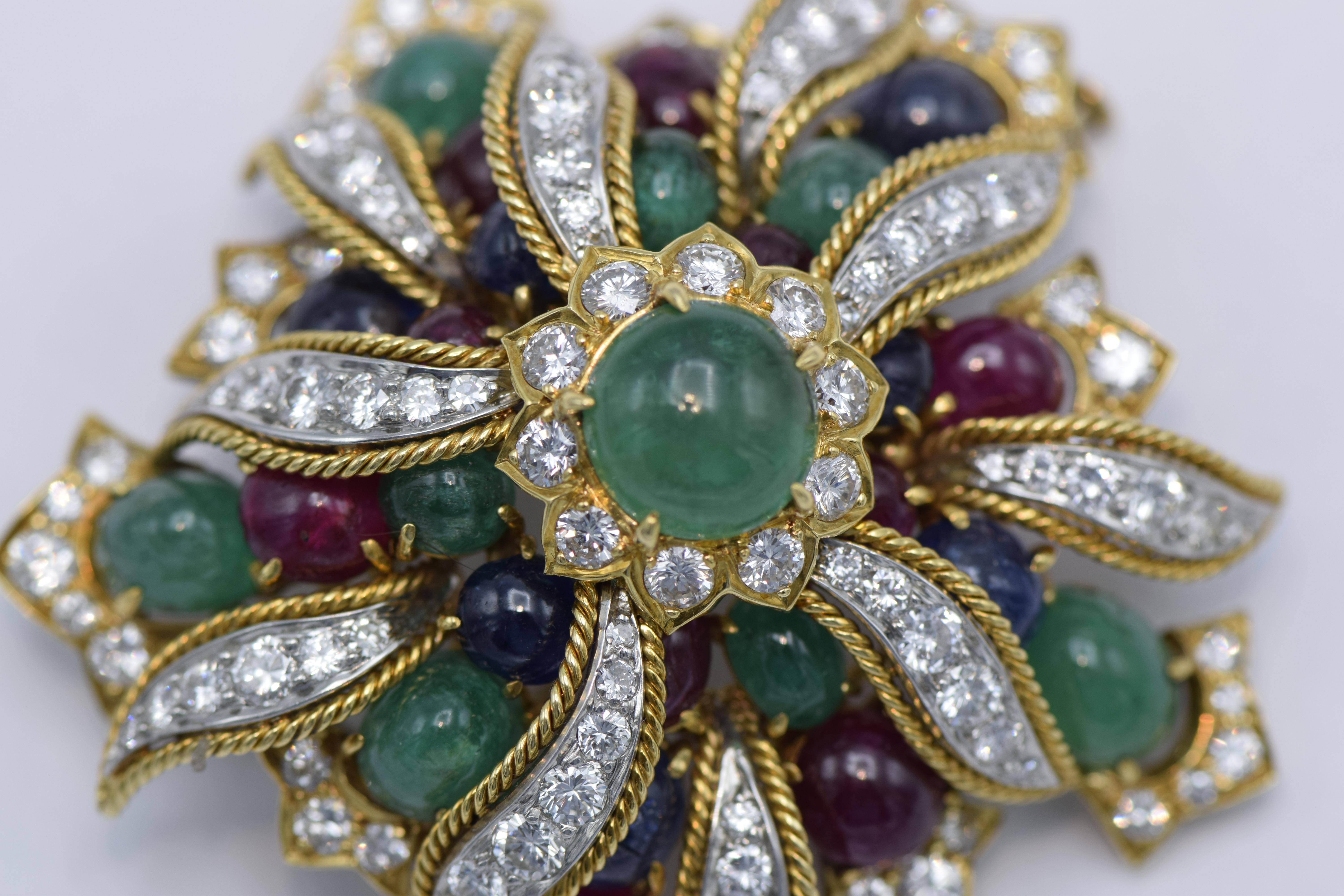 Brooch of cluster floral design, set at the center with cabochon emerald, further decorated with cabochon rubies, sapphires and emeralds, enhanced with round brilliant-cut diamond leaves, the border set with similarly cut diamonds, estimated total
