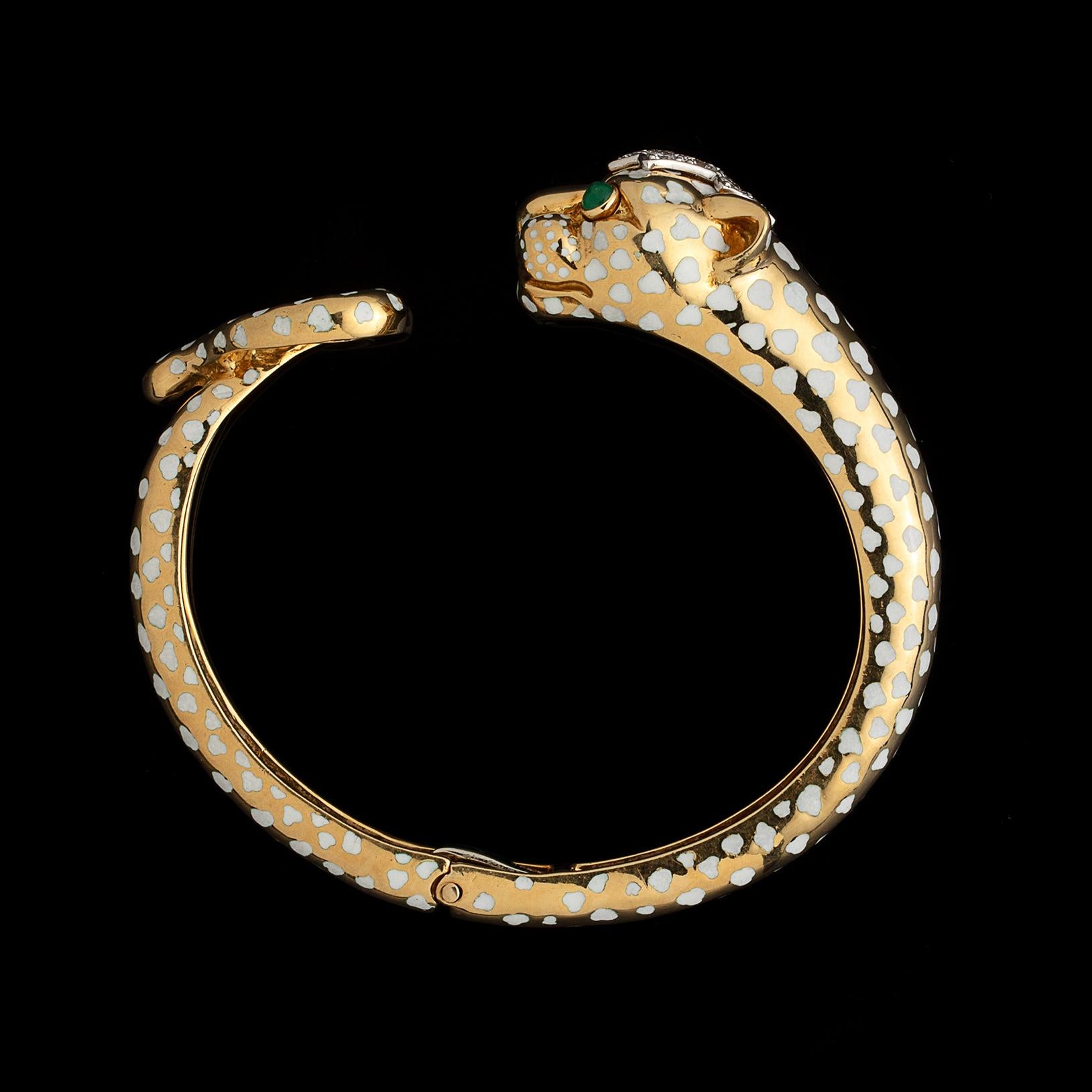 A vintage and rare find from the one and only David Webb! Circa 1980's, this 18k yellow gold David Webb panther bangle bracelet is designed white enamel spots, emerald cabochon eyes, and a head adorned with 8 round brilliant-cut diamonds set in