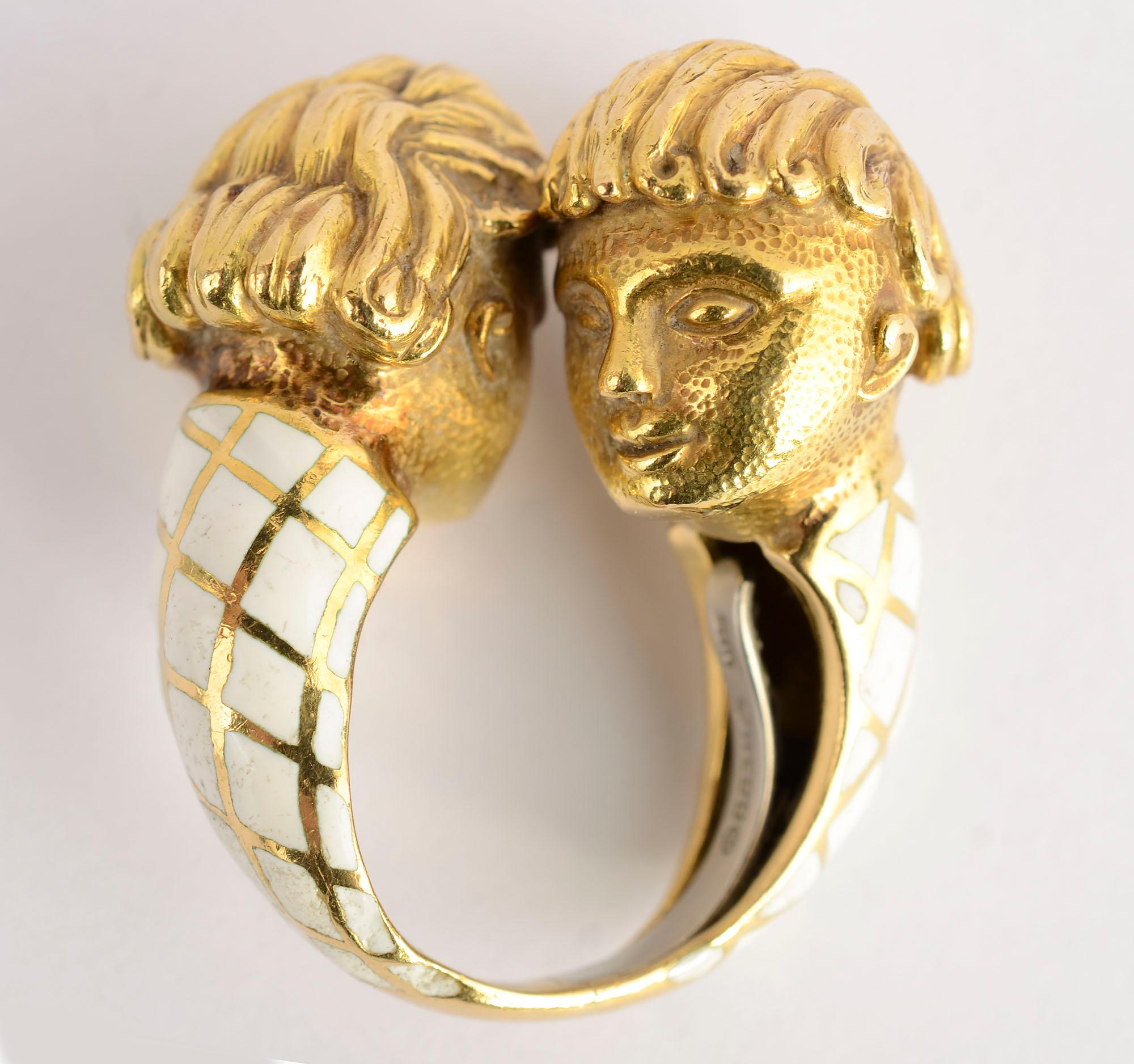 This most unusual ring by David Webb shows two faces in full three dimension. They may be cherubs or lovers as the viewer interprets. 
The body of the ring is the enamel diamond design often used by Webb. The bottom of the shank is plain gold so the