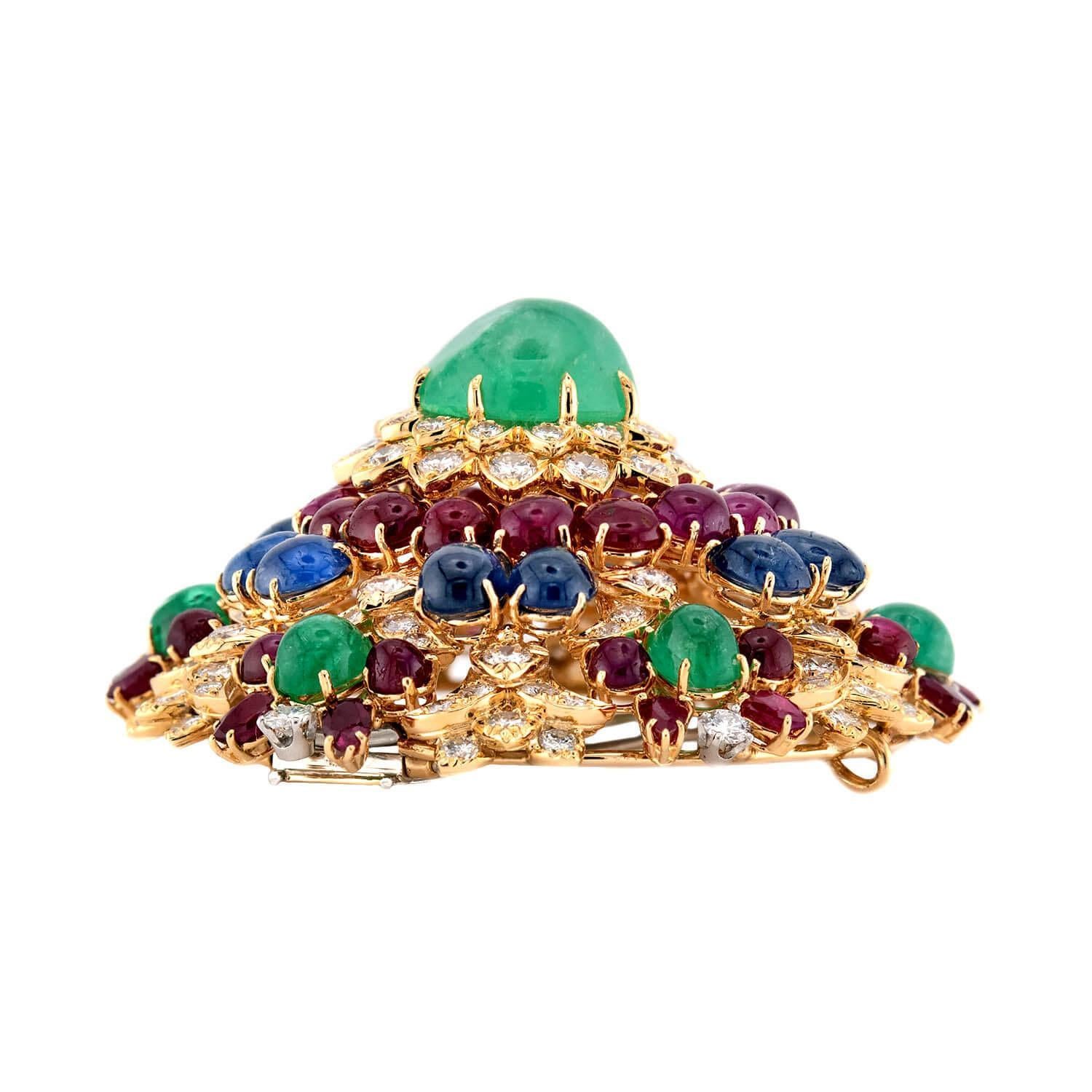 Une magnifique broche ornée du légendaire designer David Webb. Réalisée en or jaune vibrant 18 carats, cette broche au motif d'étoile est incrustée d'émeraudes, de rubis, de saphirs et de diamants. Au centre de la pièce se trouve un cabochon
